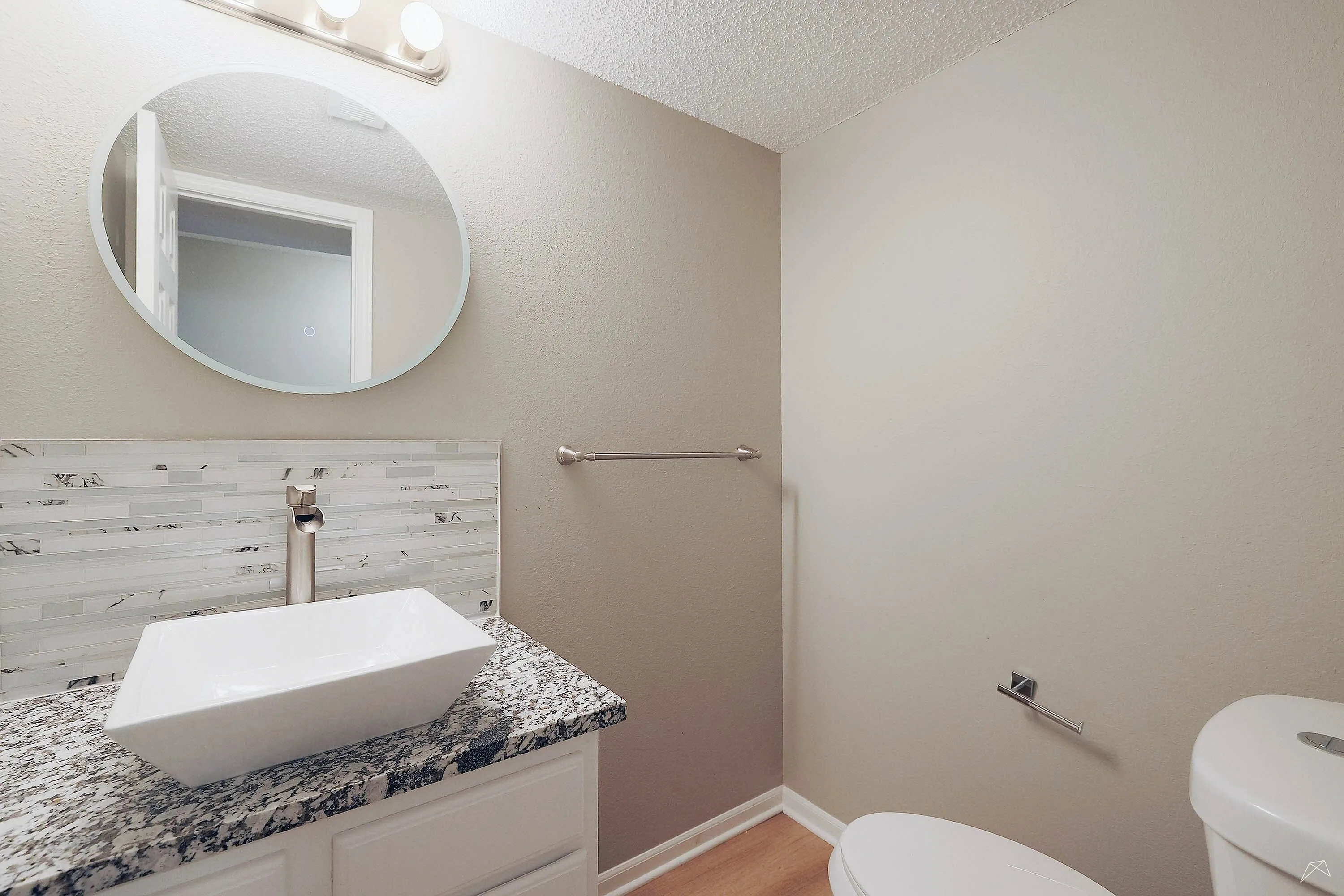 Chic bathroom showcasing a modern vessel sink with marble countertop, oval mirror, and subtle lighting for a serene ambiance.