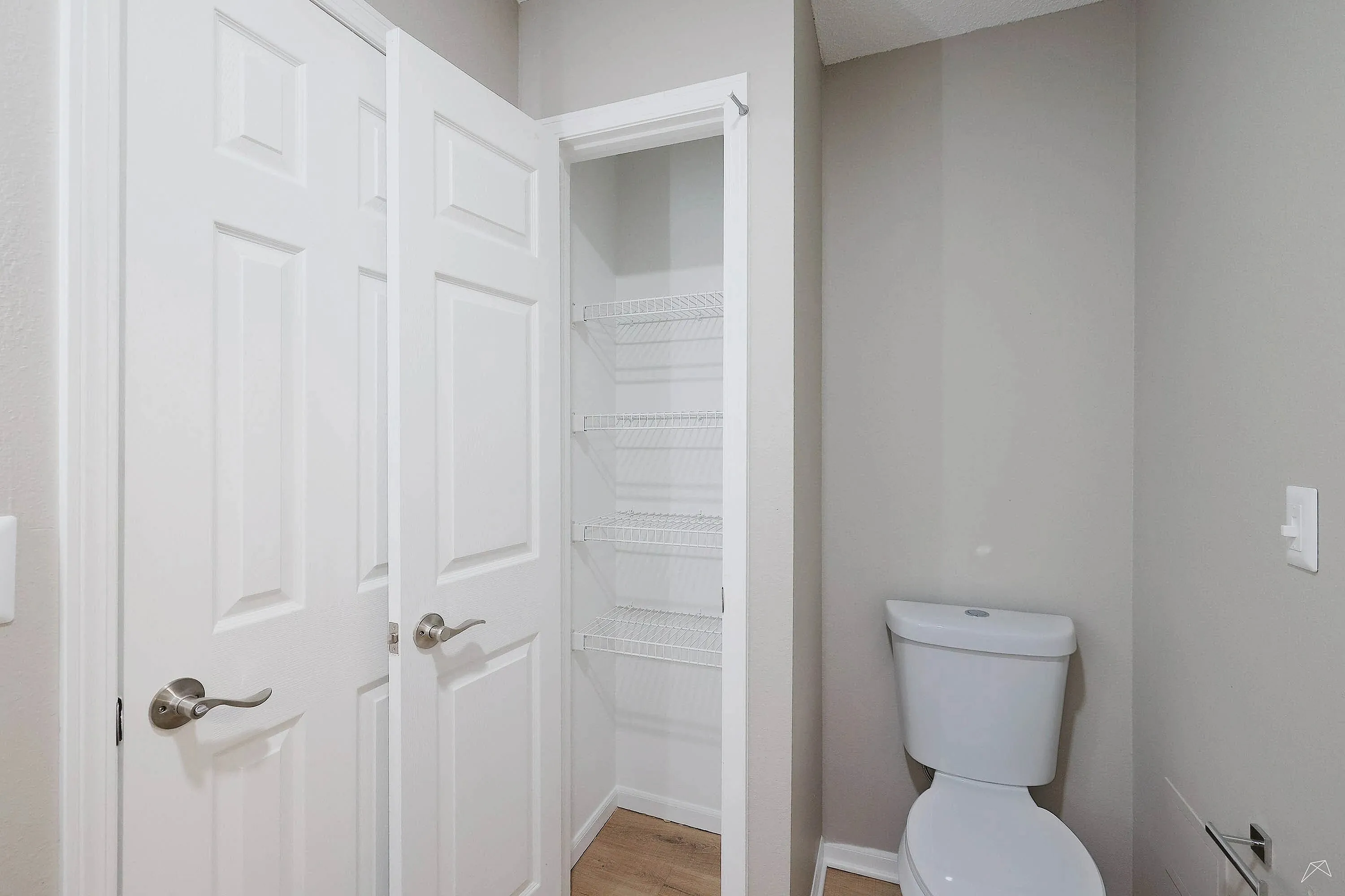 Bright apartment bathroom featuring sleek white fixtures and a convenient built-in storage closet.