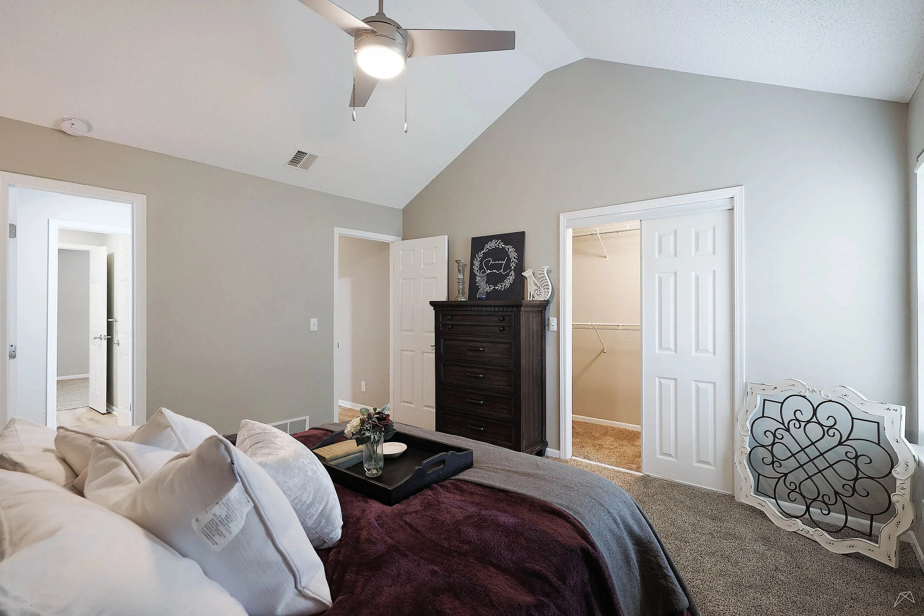 Inviting bedroom with vaulted ceiling and modern fan, featuring a large walk-in closet and elegant décor.
