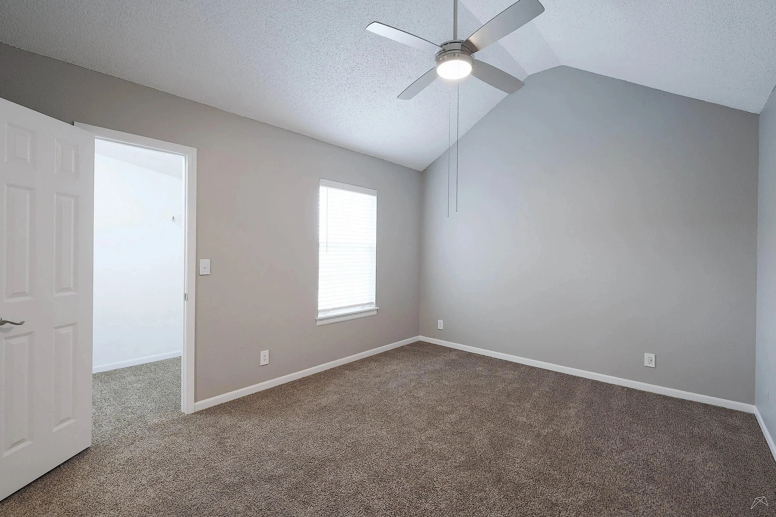 Elegant room with a high ceiling, modern ceiling fan, and plush carpet, perfect for a cozy and inviting atmosphere.