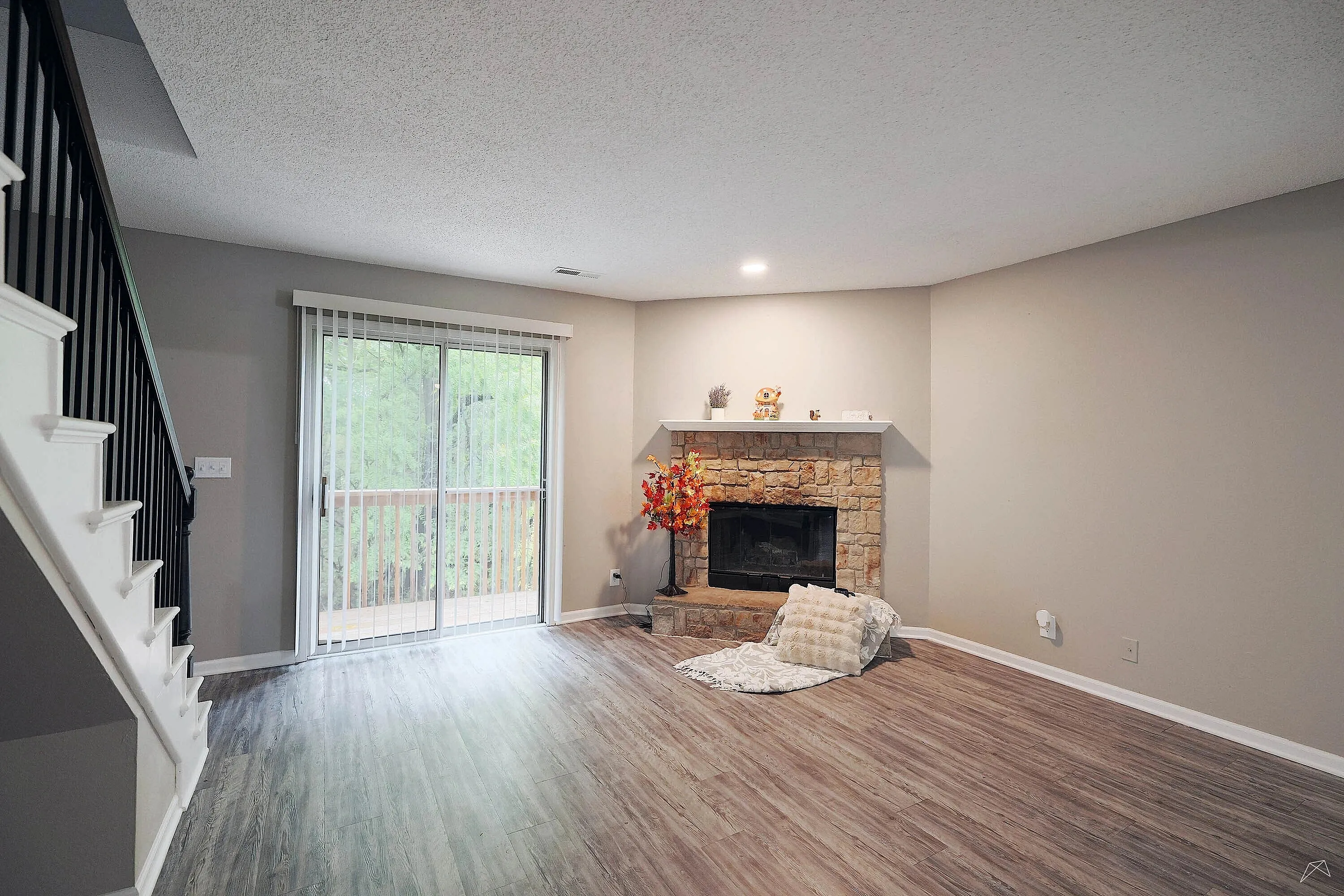 Bright living room with modern flooring, cozy stone fireplace, and sliding glass doors opening to scenic views.