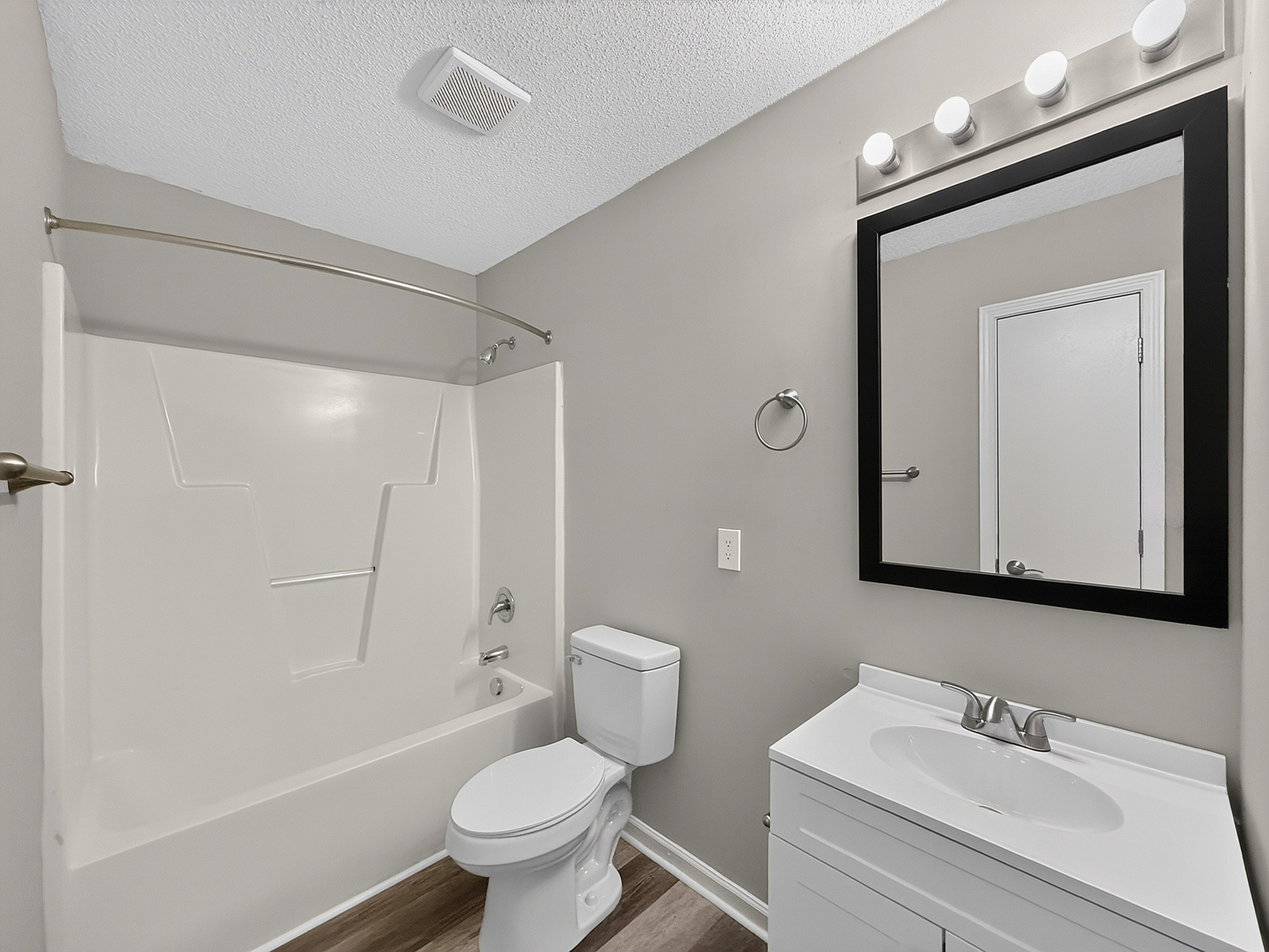 Modern bathroom with sleek design, showcasing a pristine white bathtub, elegant vanity with bright lighting, and stylish fixtures.