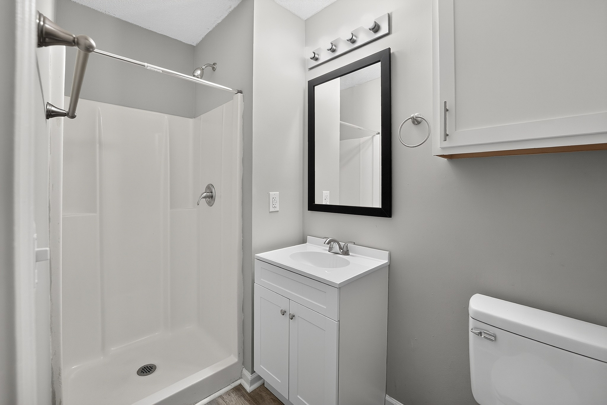 Modern bathroom with sleek white shower, elegant vanity, and bright lighting fixtures.