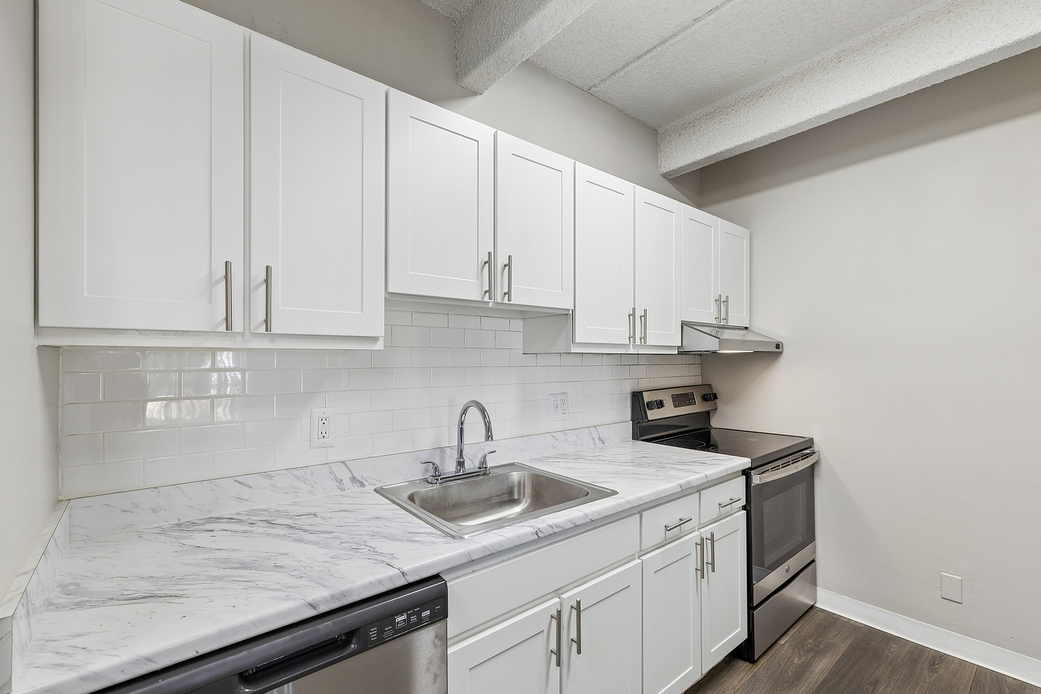 Modern kitchen with sleek white cabinetry, marble countertops, and stainless steel appliances in a stylish apartment.