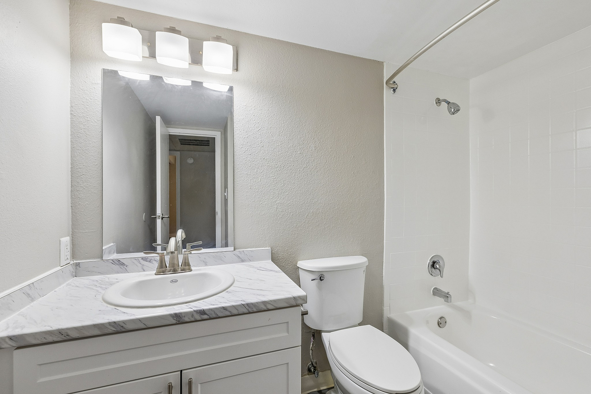 Modern bathroom with elegant marble countertop, stylish vanity, and bright overhead lighting, complementing a sleek white bathtub.