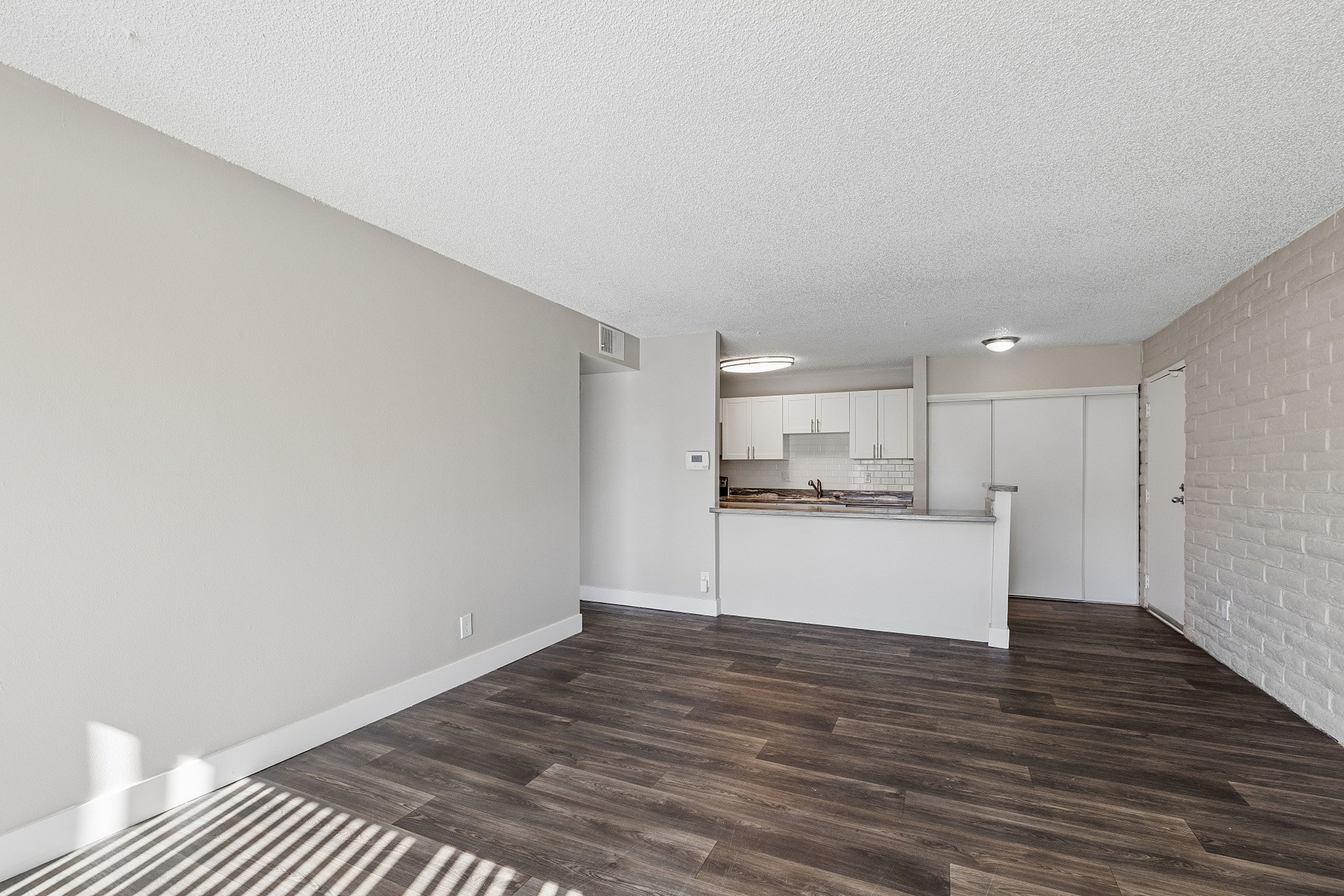 Modern open-plan layout with sleek wooden flooring and a stylish kitchen featuring white cabinetry and elegant countertops.