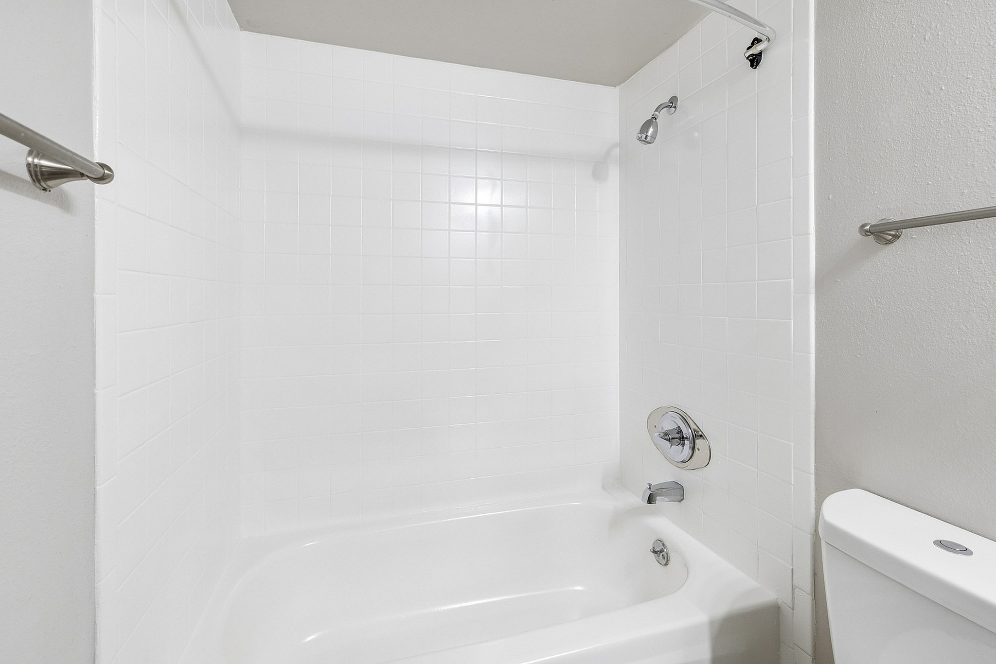 Bright and modern bathroom featuring a pristine white tiled shower and bathtub combo, complemented by sleek fixtures.