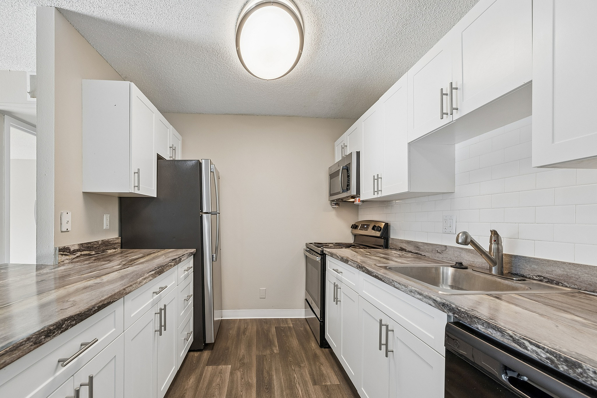 Contemporary kitchen with sleek stainless steel appliances, elegant white cabinetry, and modern countertops, boasting a stylish and functional design.