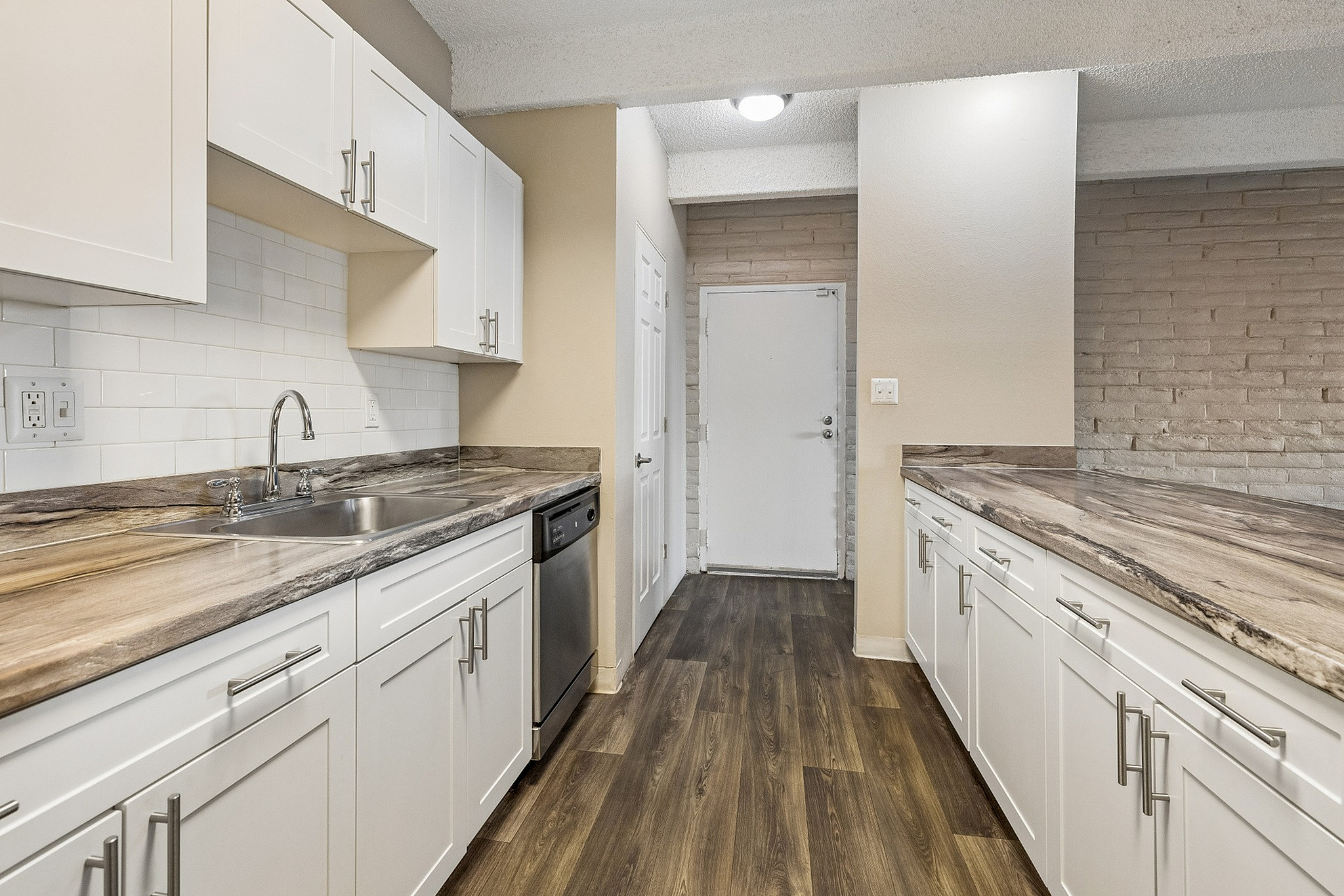 Chic modern kitchen with sleek granite countertops, white cabinetry, and elegant hardwood flooring.