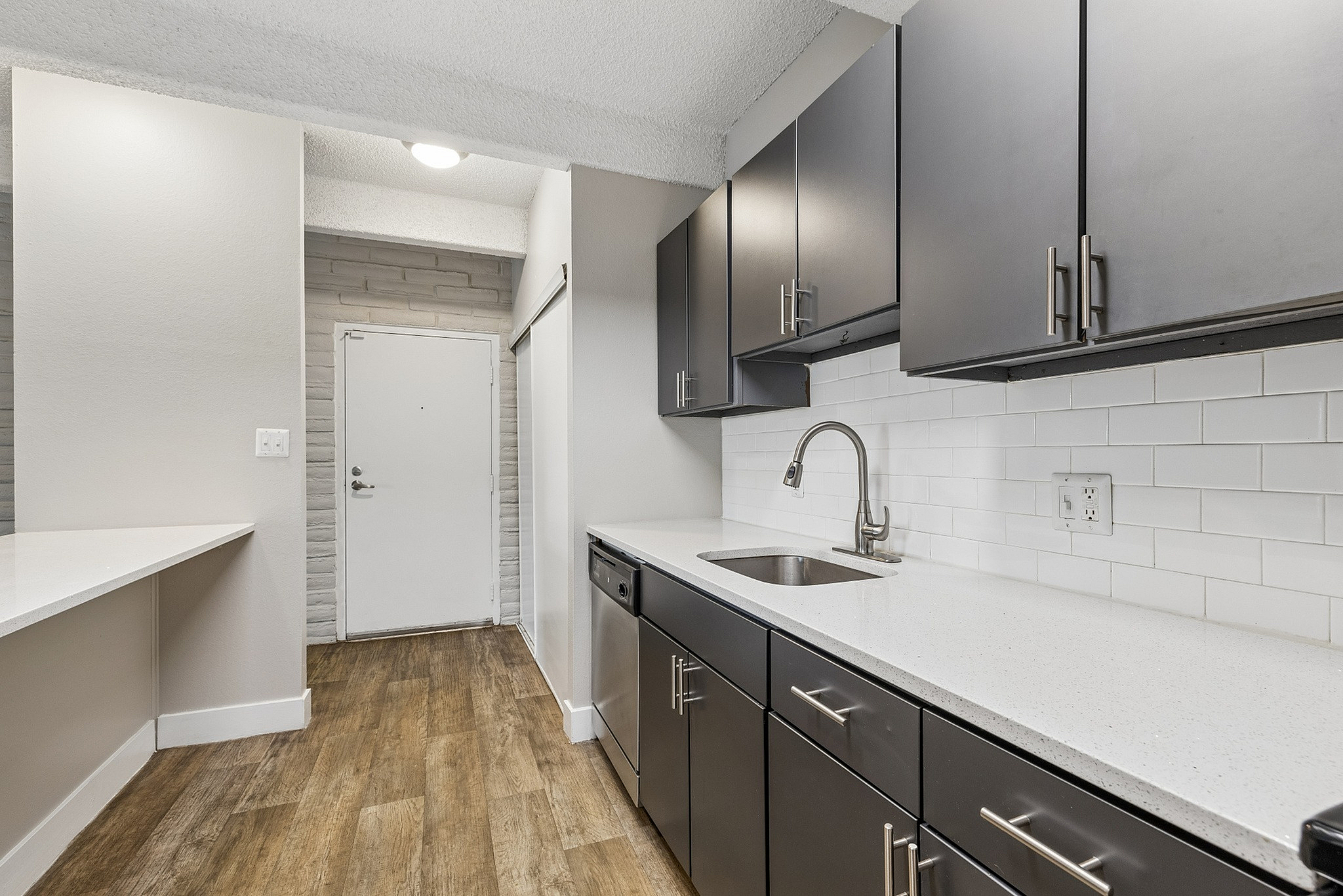 Modern kitchen with sleek dark cabinetry, elegant white countertops, and stylish subway tile backsplash, creating a chic and inviting cooking area.