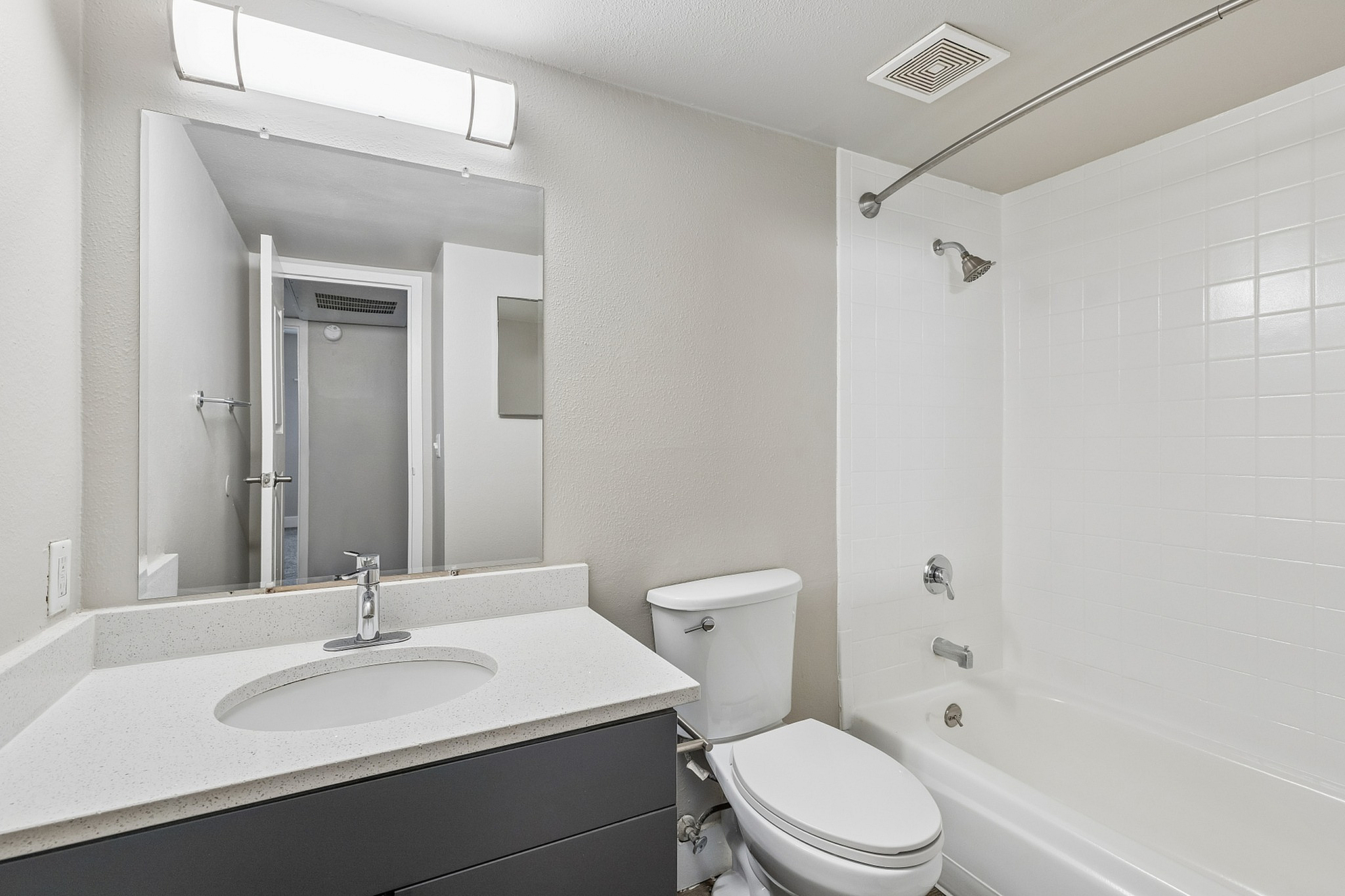 Sleek modern bathroom featuring a pristine white bathtub, contemporary sink, and stylish lighting.