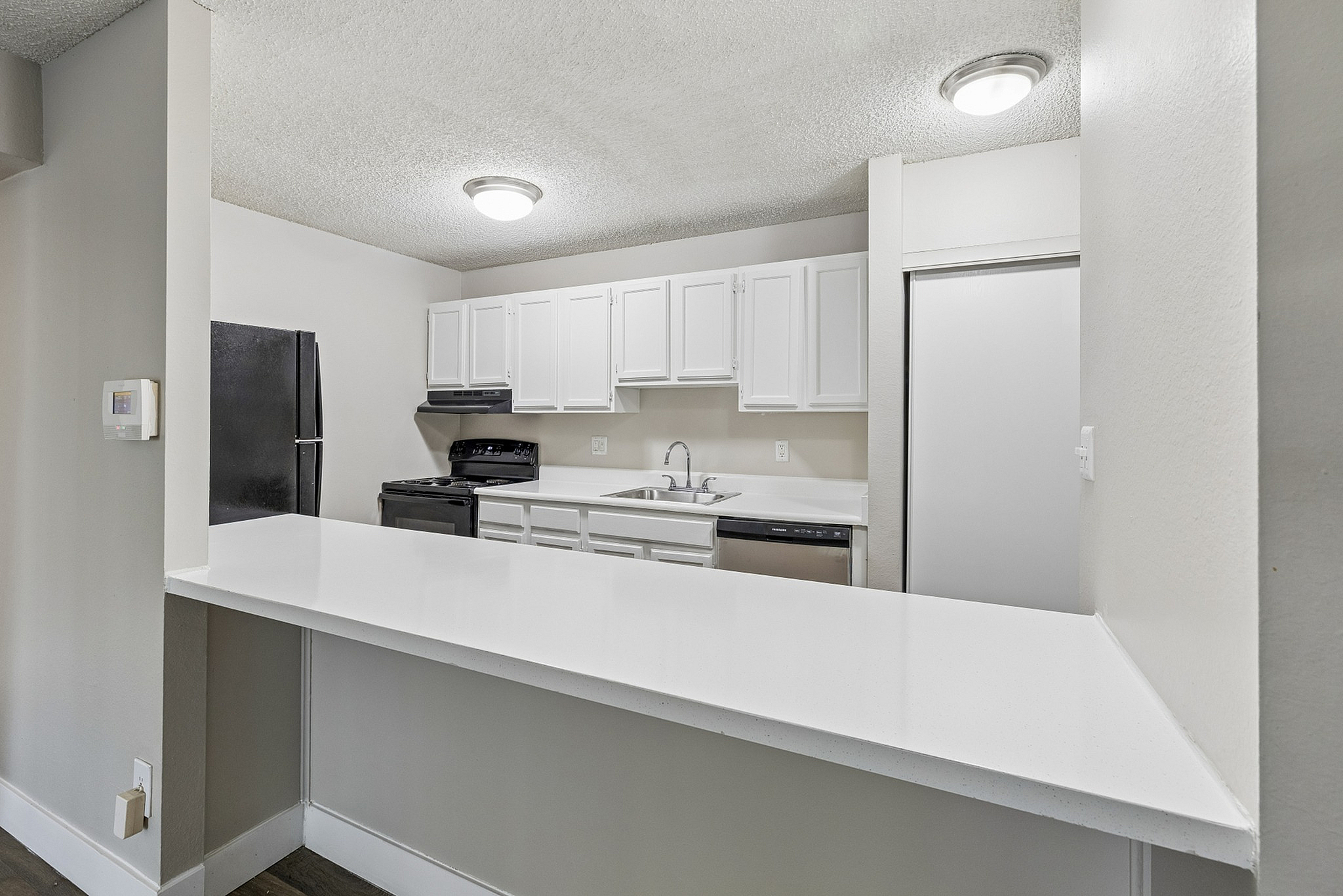 Modern kitchen design with sleek white cabinetry, black appliances, and a spacious countertop for dining or prep.