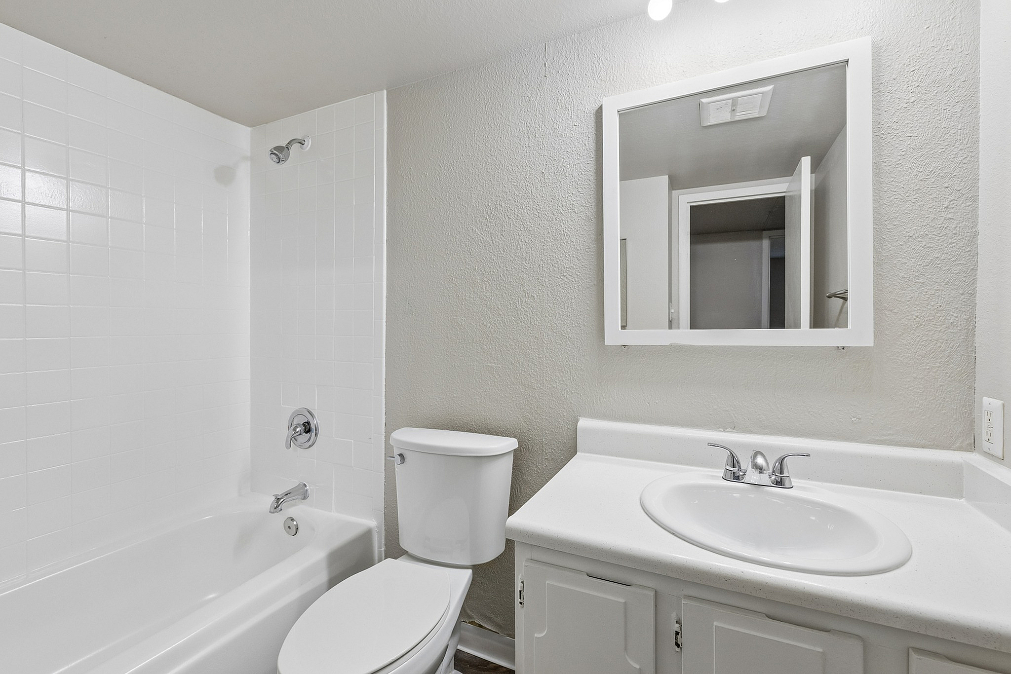Bright and modern bathroom featuring a sleek white bathtub, matching vanity, and a large mirror.