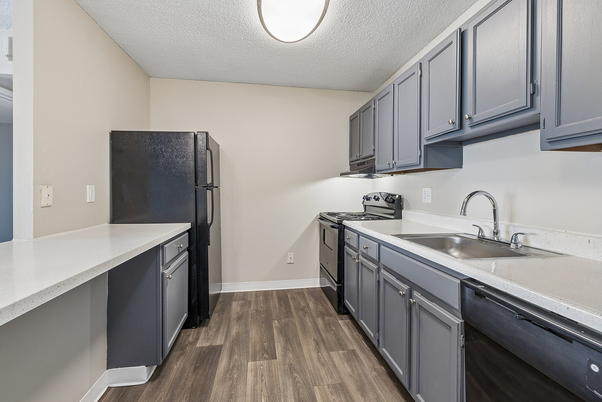 Modern kitchen with sleek countertops, elegant gray cabinets, and stainless fixtures, complemented by stylish wood flooring.