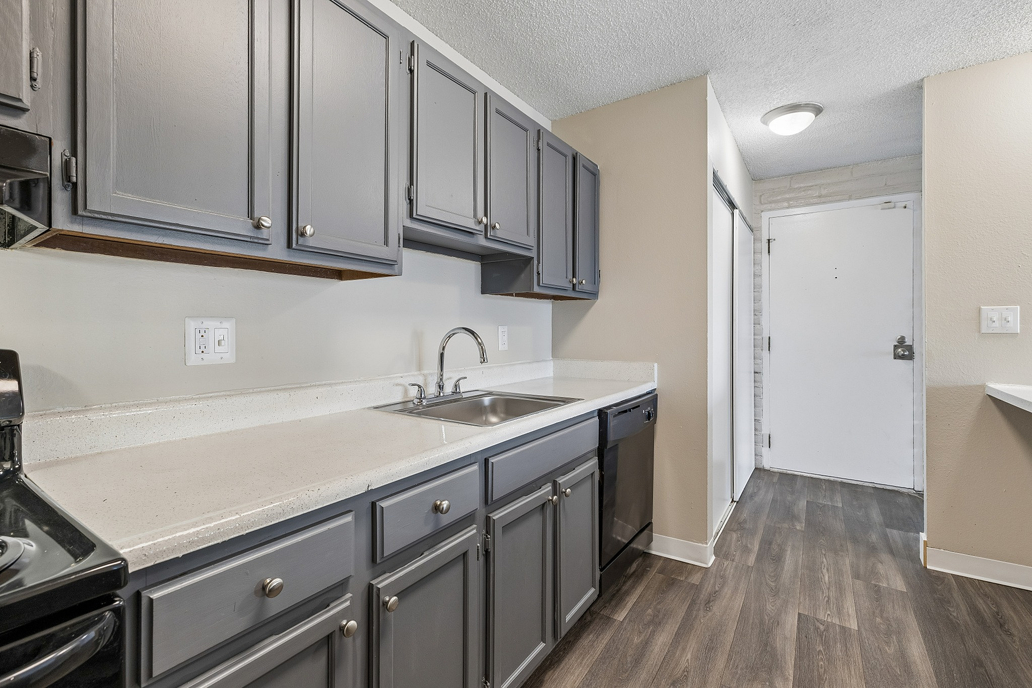 Contemporary kitchen with sleek gray cabinets, modern appliances, and elegant wood flooring, creating a stylish and functional space.