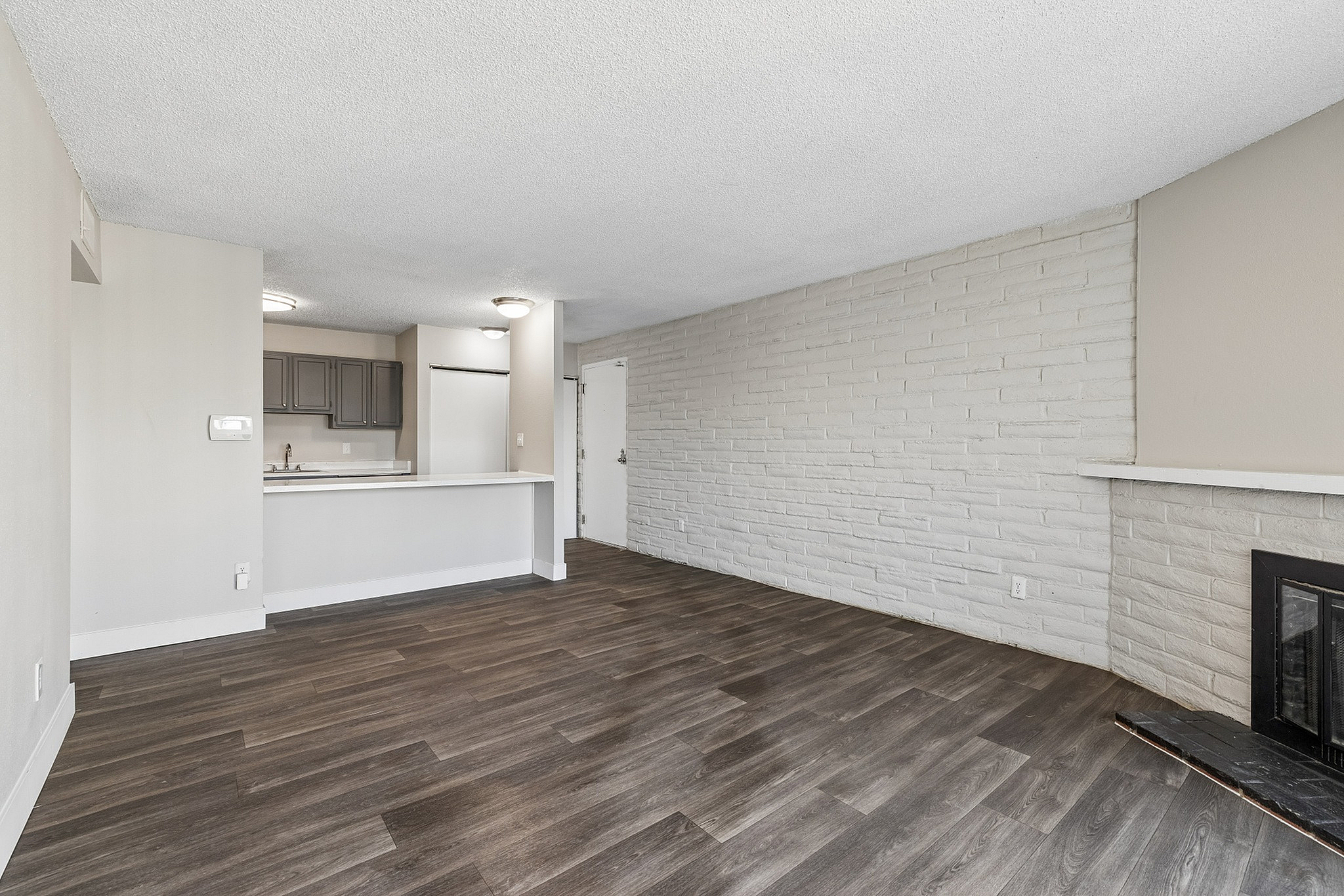 Modern open-concept living area with sleek wood flooring, contemporary fireplace, and a spacious kitchen island.