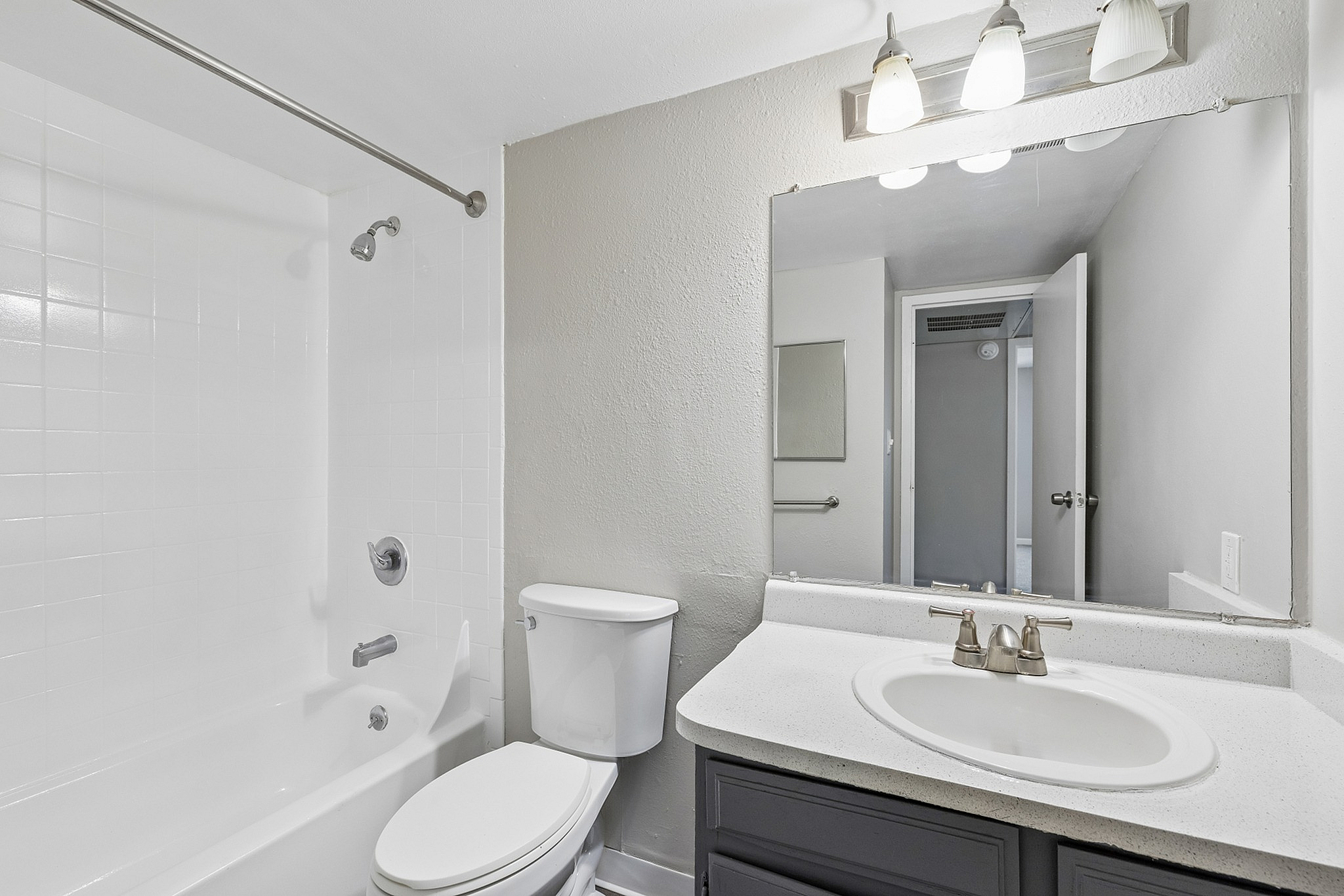 Modern bathroom showcasing a sleek vanity, large mirror, and pristine white bathtub with elegant fixtures.