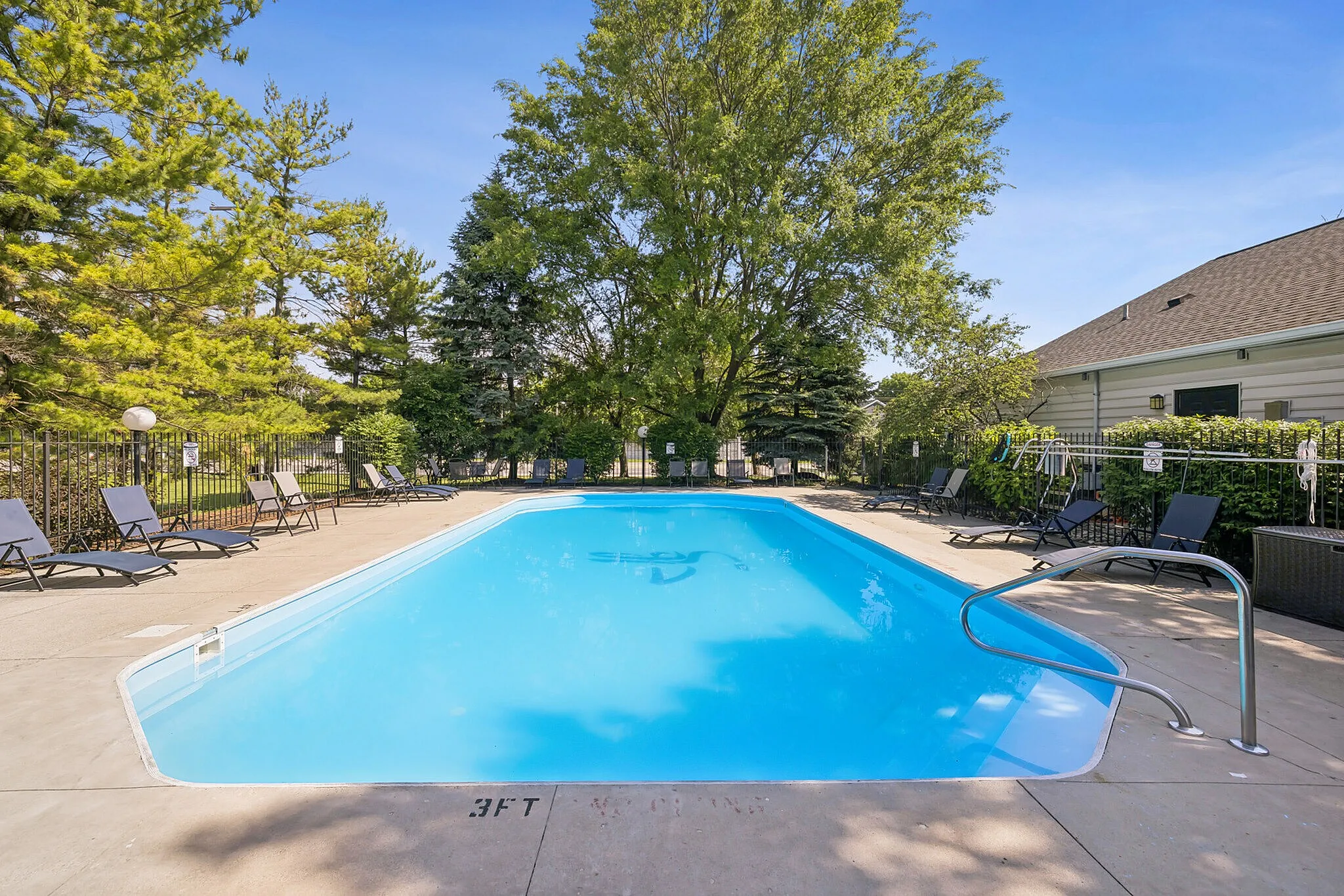 Inviting outdoor pool area surrounded by lush greenery and comfortable lounge chairs, perfect for relaxation and enjoying sunny days.