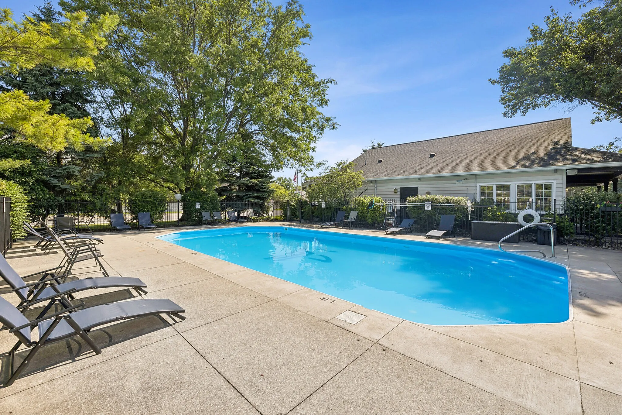 Inviting outdoor pool area surrounded by lush greenery and comfortable lounge chairs, perfect for relaxation and leisure.
