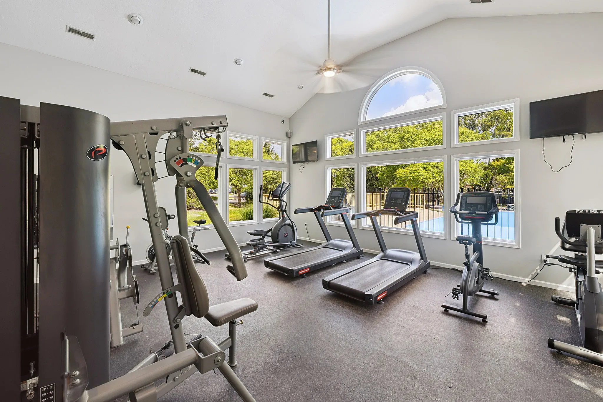 Bright and airy gym with modern cardio and strength equipment in a light-filled space with large windows.