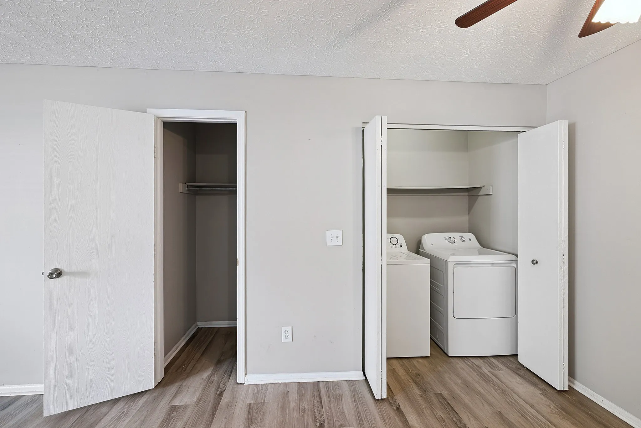 Modern apartment featuring a stylish laundry area with washer and dryer next to a spacious closet, set against elegant wooden flooring.