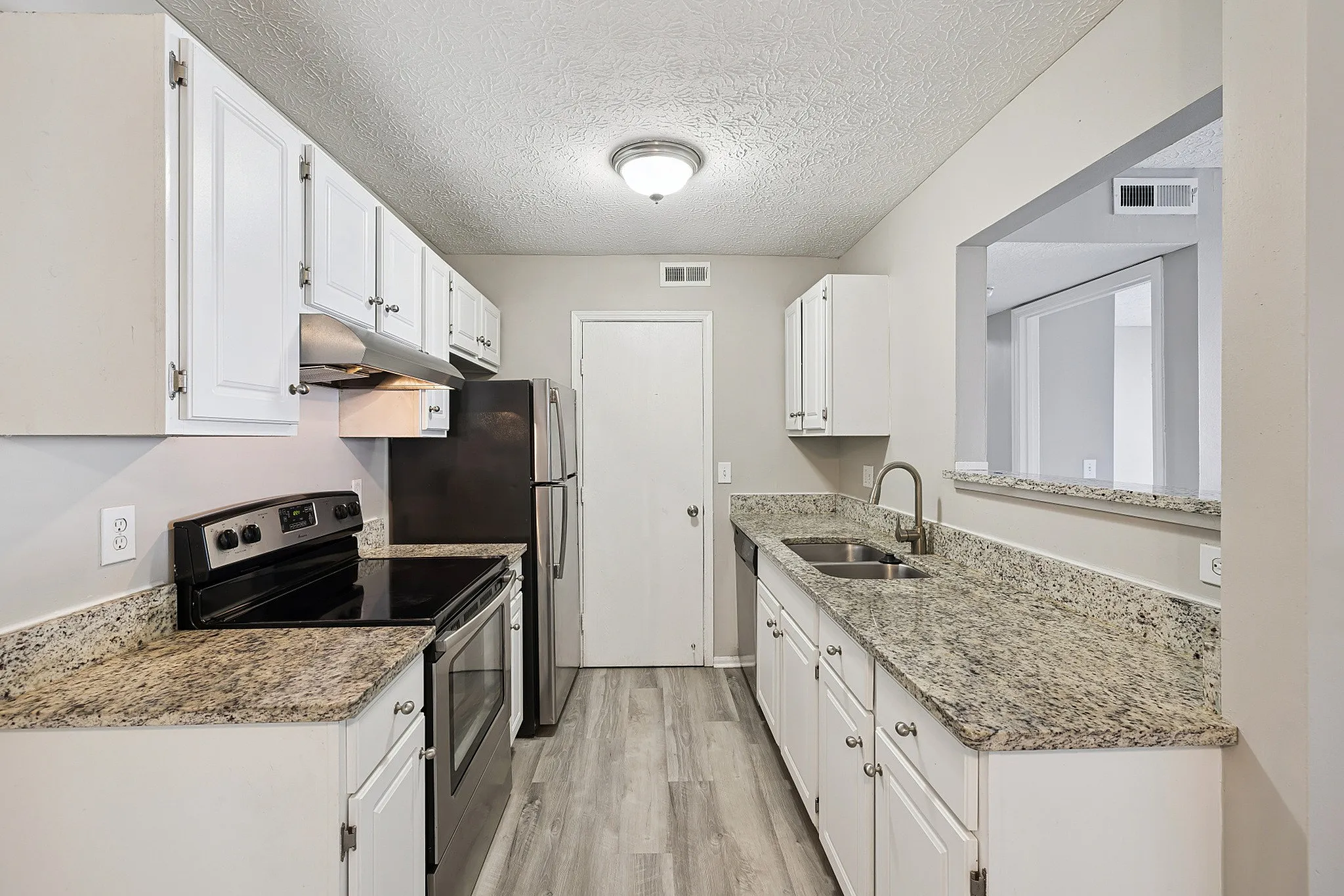Modern kitchen with sleek stainless steel appliances, granite countertops, and white cabinetry.