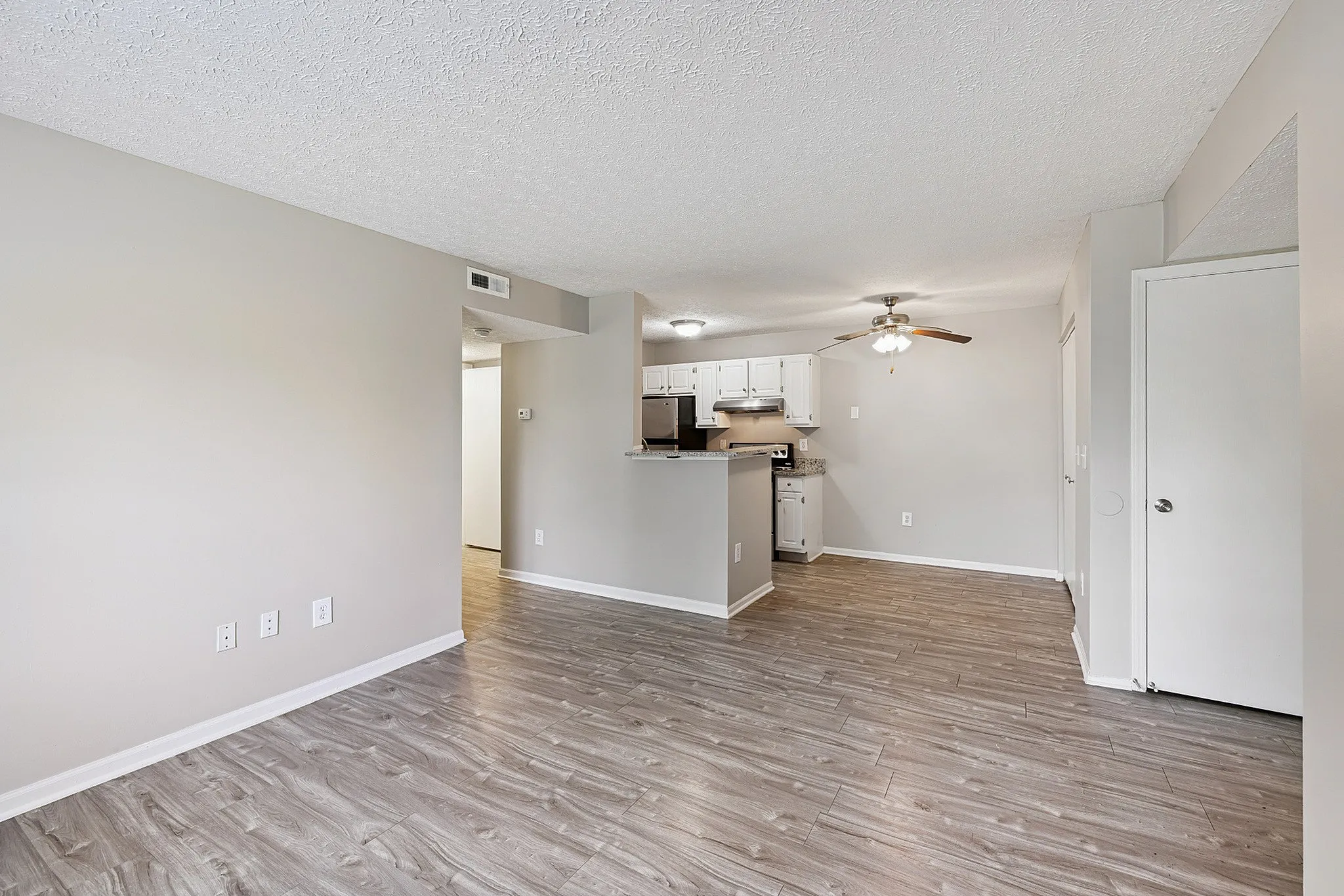 Chic open-concept living space with elegant wood flooring and a modern kitchen setup.