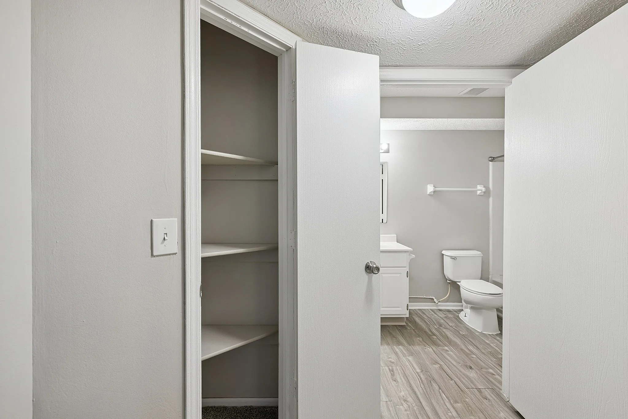 Modern bathroom with elegant gray walls, sleek white fixtures, and ample storage space featuring built-in shelving.