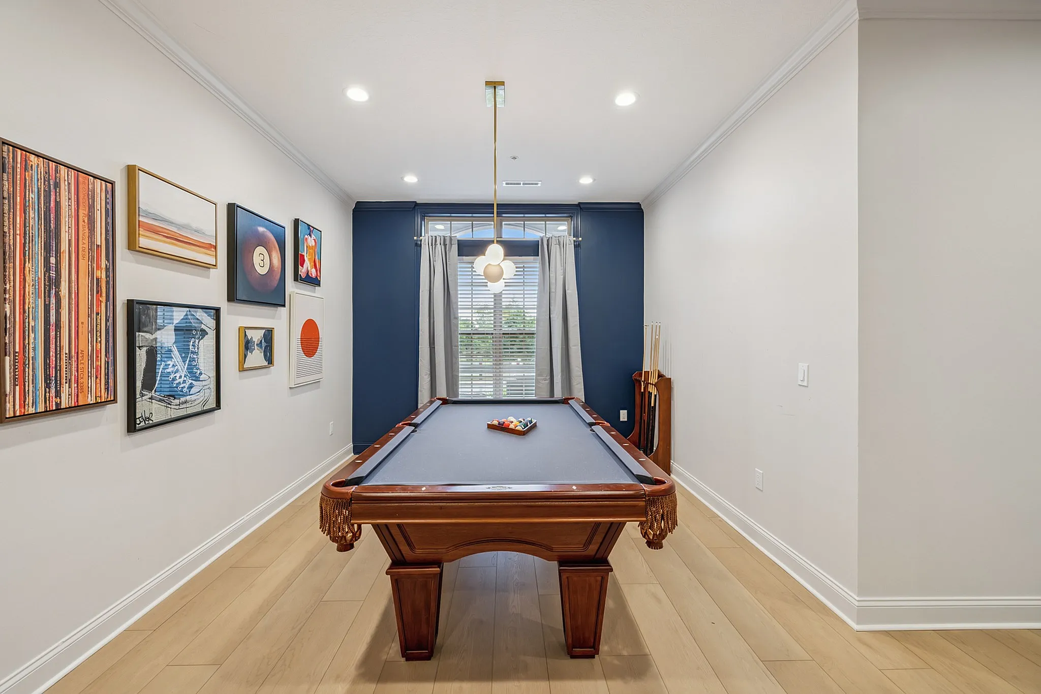 Chic game room with a classic pool table, art-adorned walls, and elegant lighting creating a stylish retreat.
