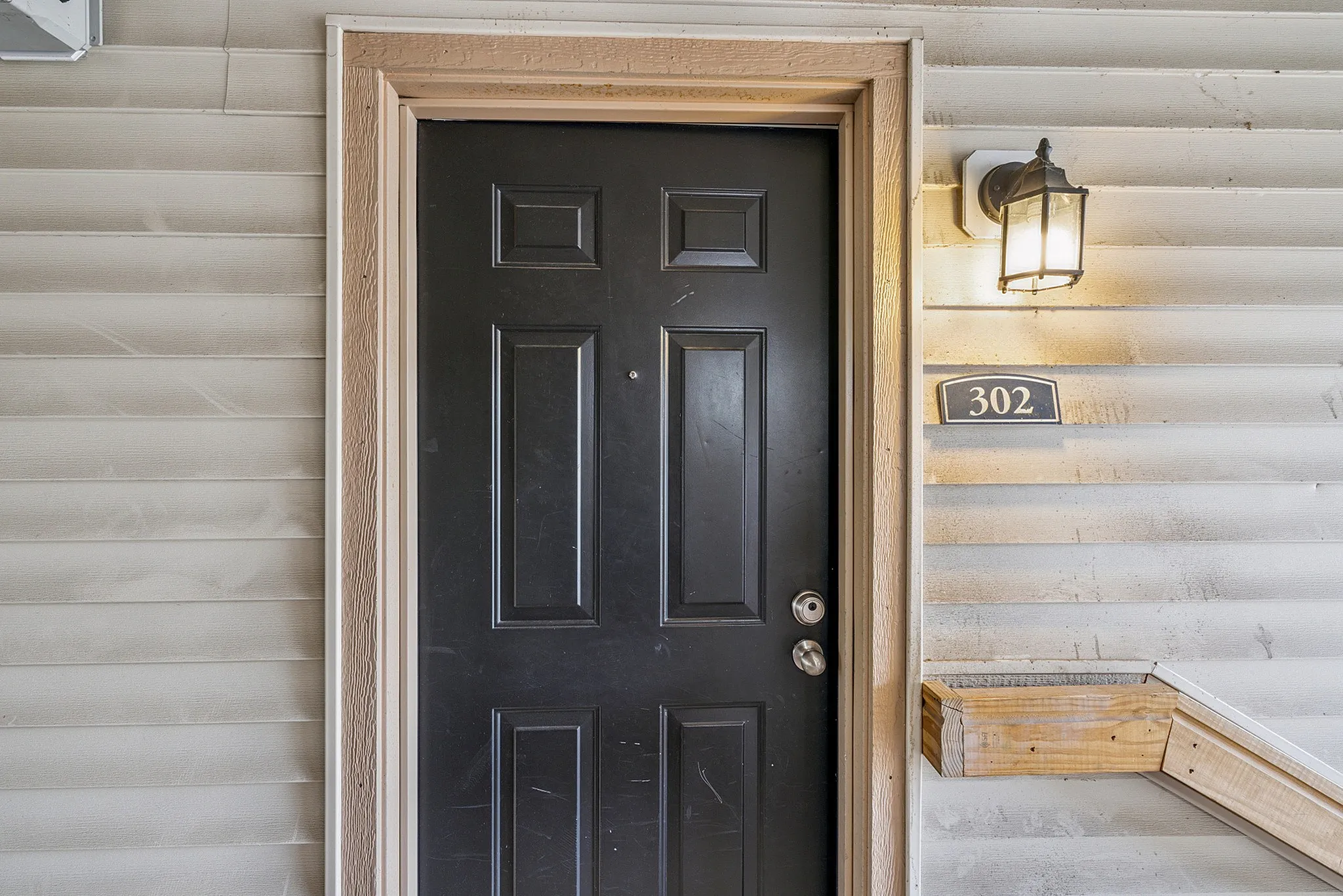 Charming apartment entrance with elegant black door and warm lighting, inviting atmosphere at unit 302.