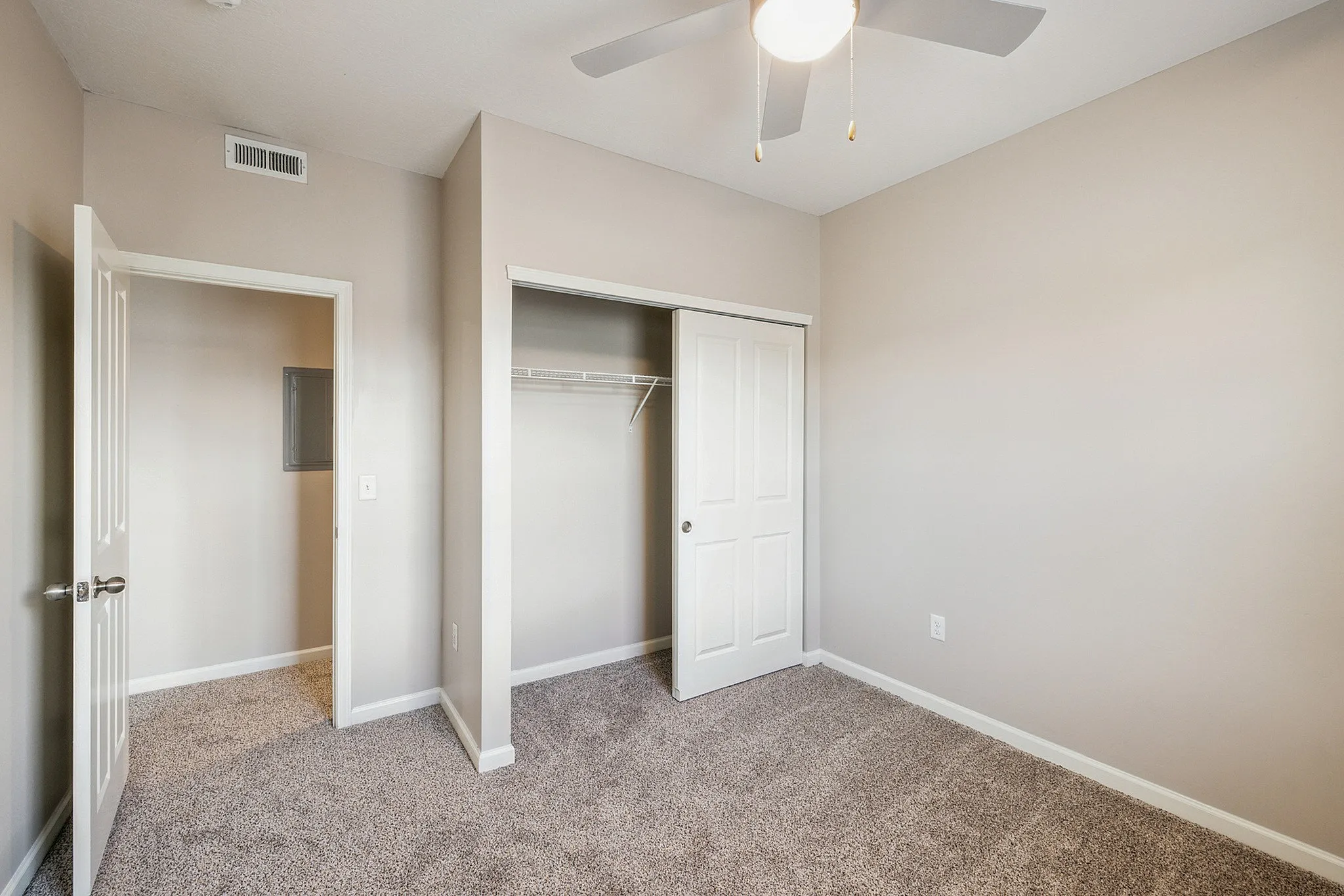 Bright, modern bedroom with plush carpeting, a built-in closet, and a ceiling fan for comfort.