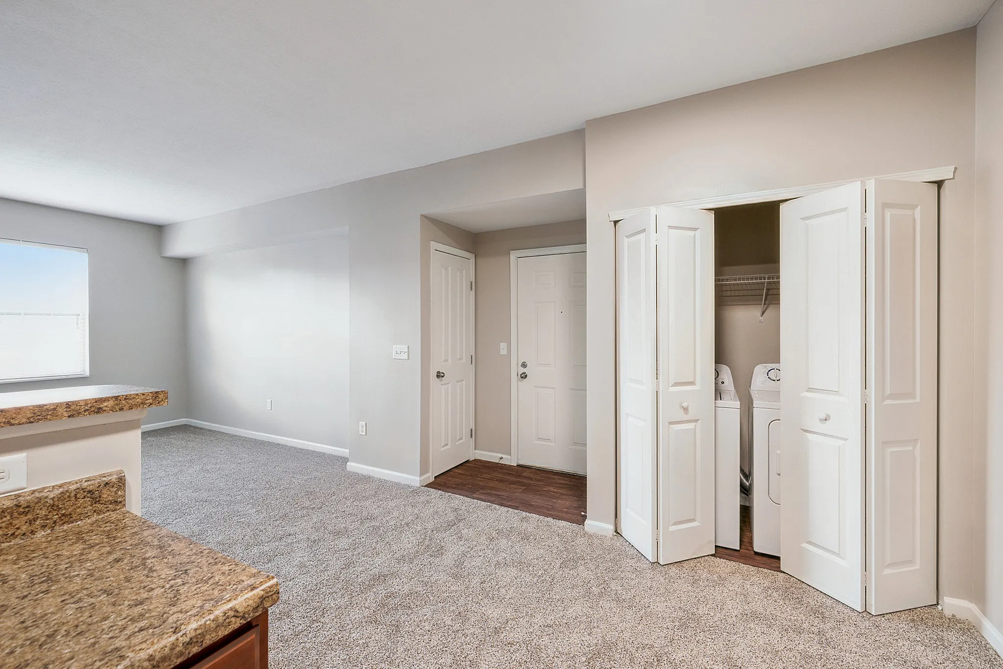 Bright and spacious apartment interior featuring plush carpet, a convenient in-unit laundry area, and modern finishes.