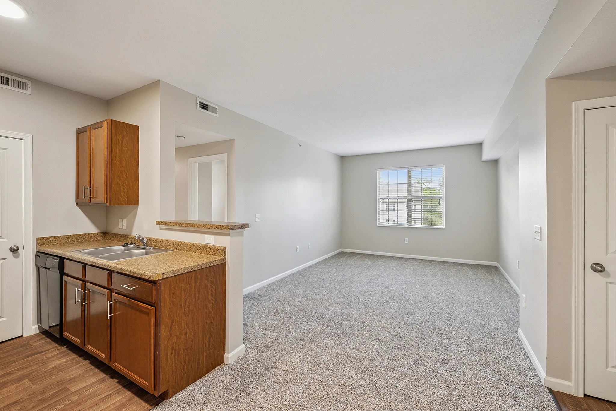 Bright and inviting open-concept living space with modern kitchen featuring sleek wood cabinets and granite countertops.