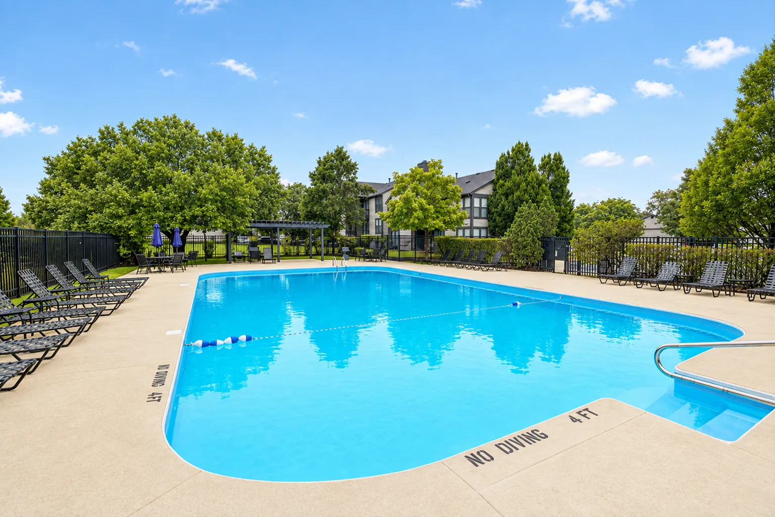 Inviting outdoor swimming pool surrounded by lush greenery and comfortable lounge chairs, perfect for relaxation and leisure.