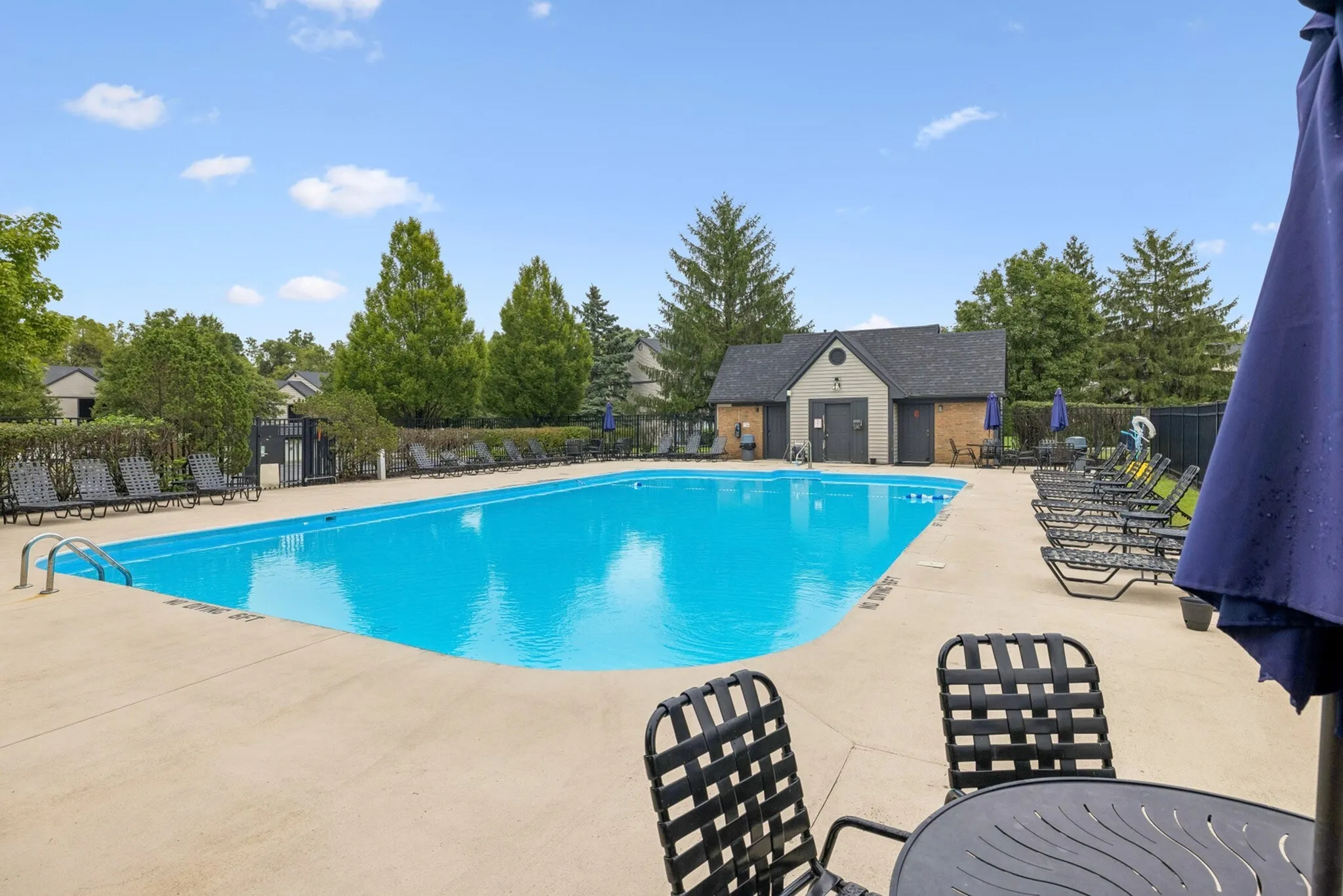 Inviting outdoor pool with vibrant blue water, surrounded by lush greenery and stylish lounge chairs for relaxation.