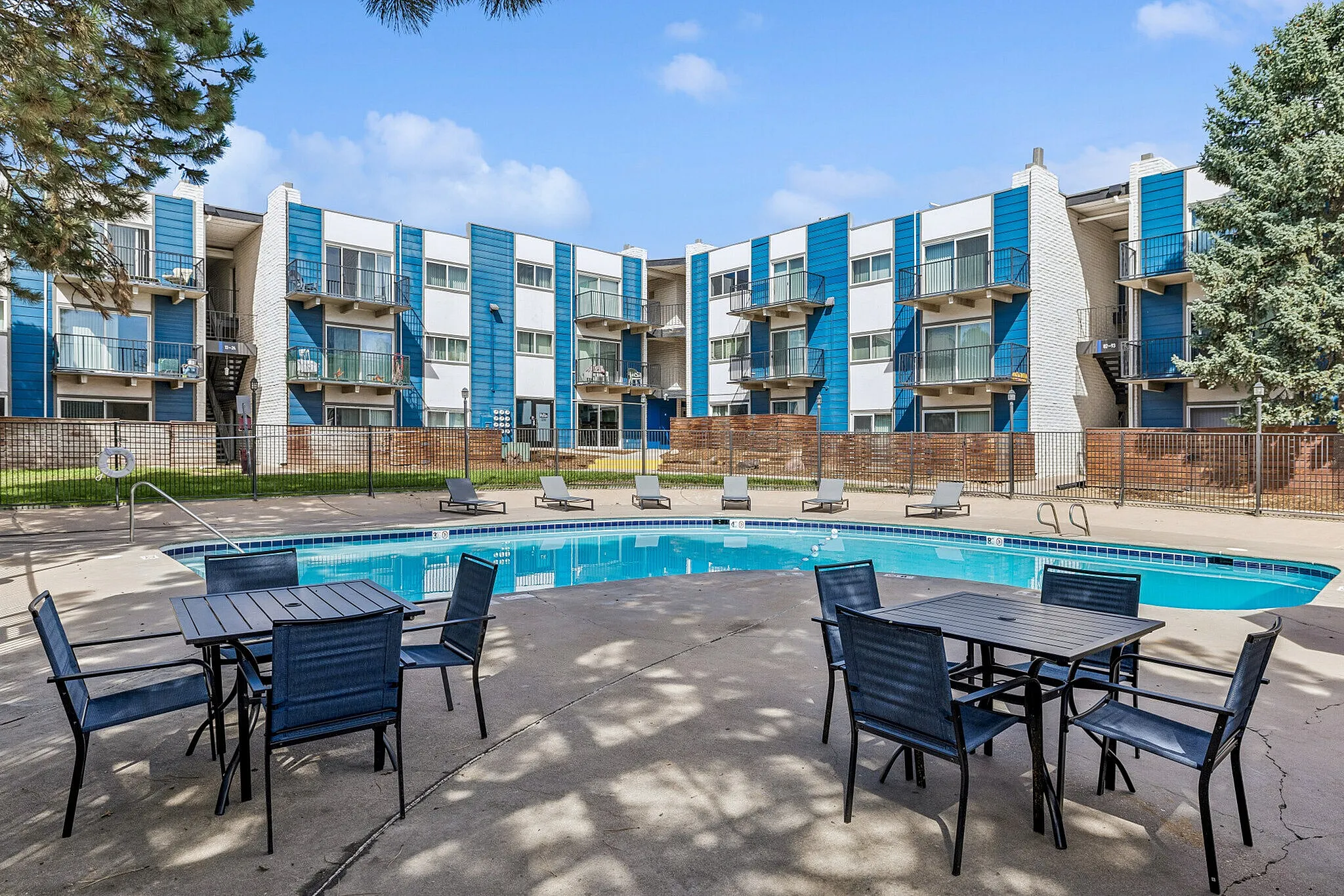 Inviting apartment complex with a refreshing pool, modern architecture, and outdoor seating area, perfect for relaxation and leisure.