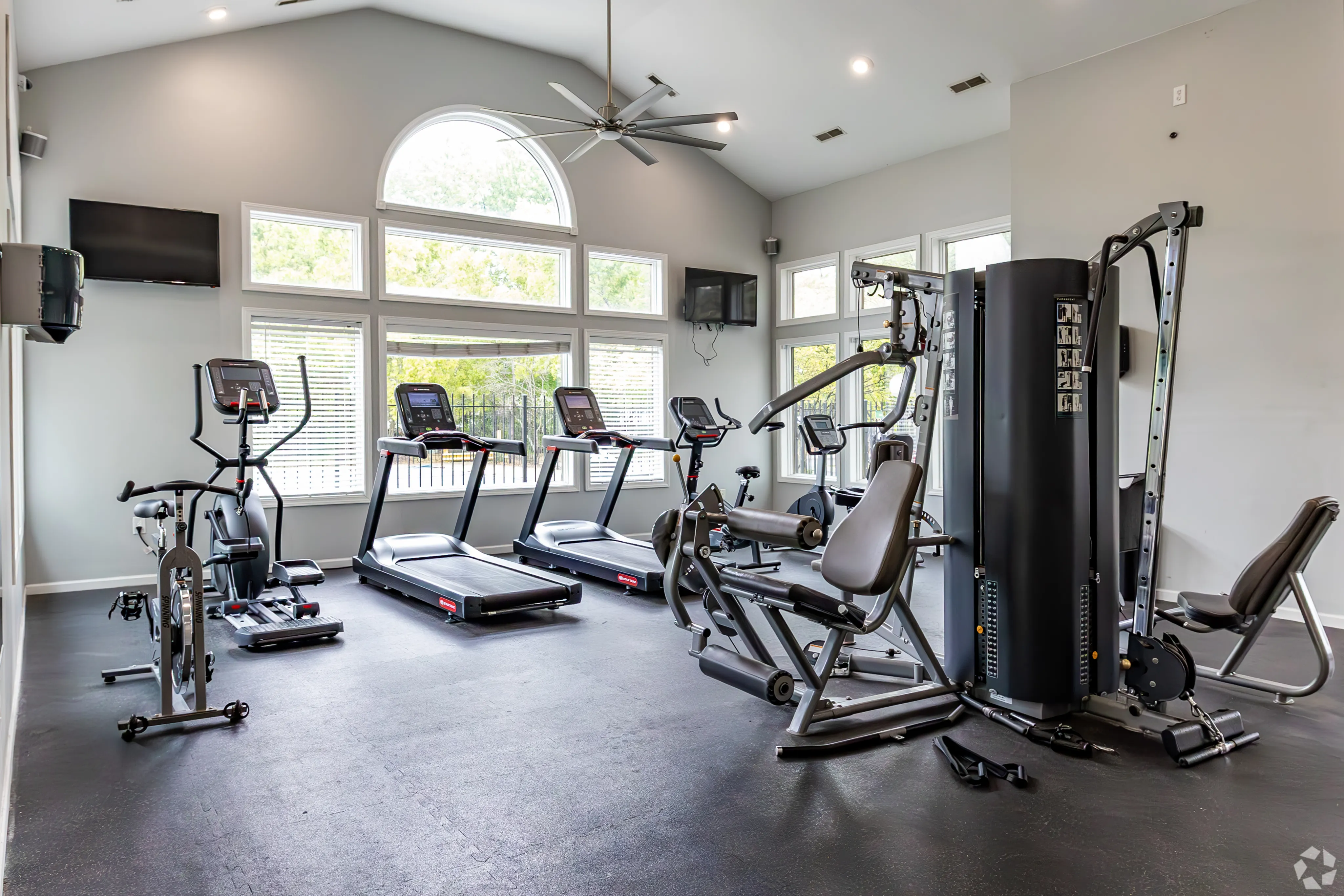 Bright and modern fitness center equipped with treadmills, exercise bikes, and strength training machines, featuring large windows with scenic views.