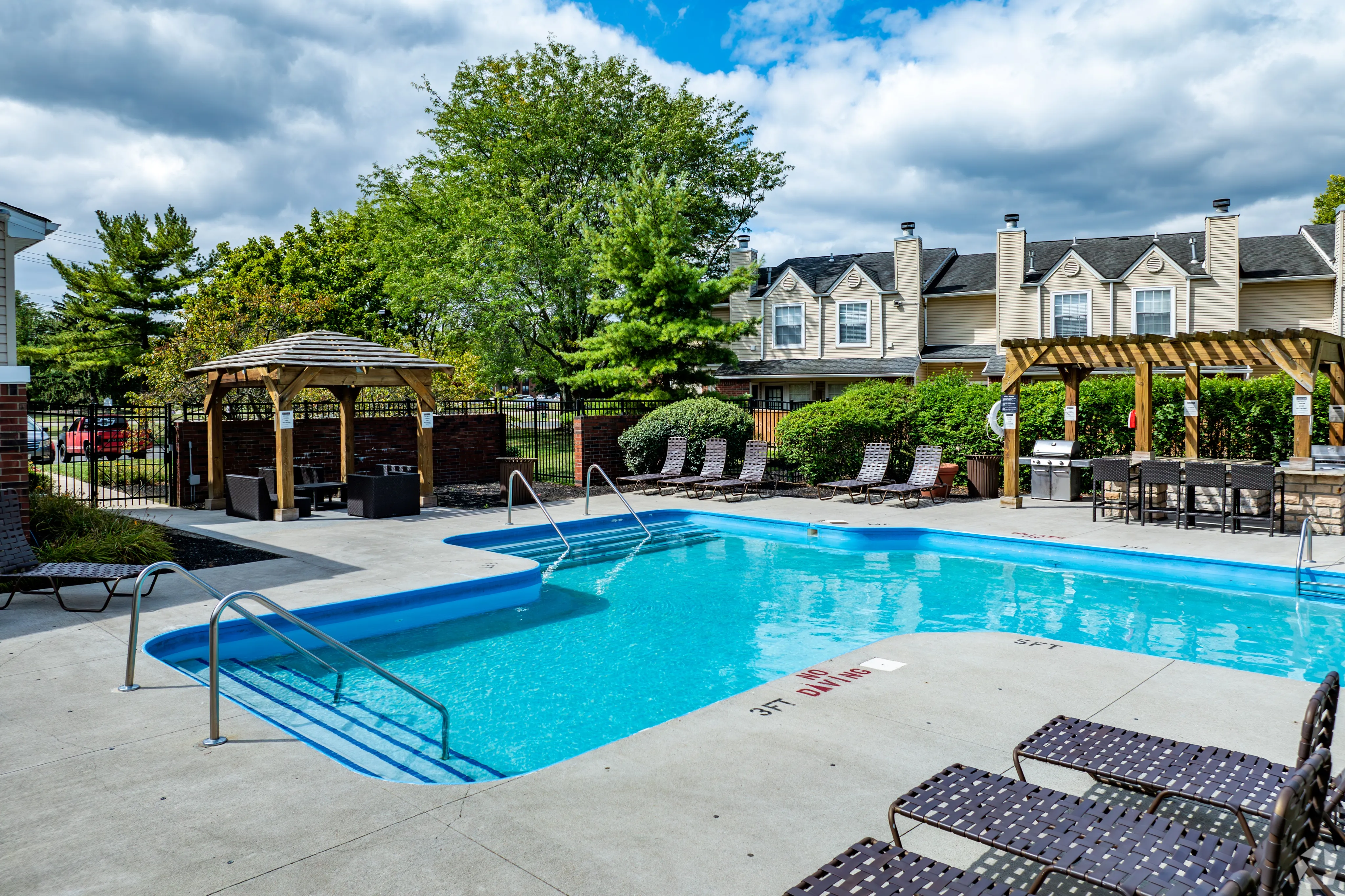 Inviting outdoor pool area with sun loungers, a charming pergola, and lush landscaping, perfect for relaxation and gatherings.