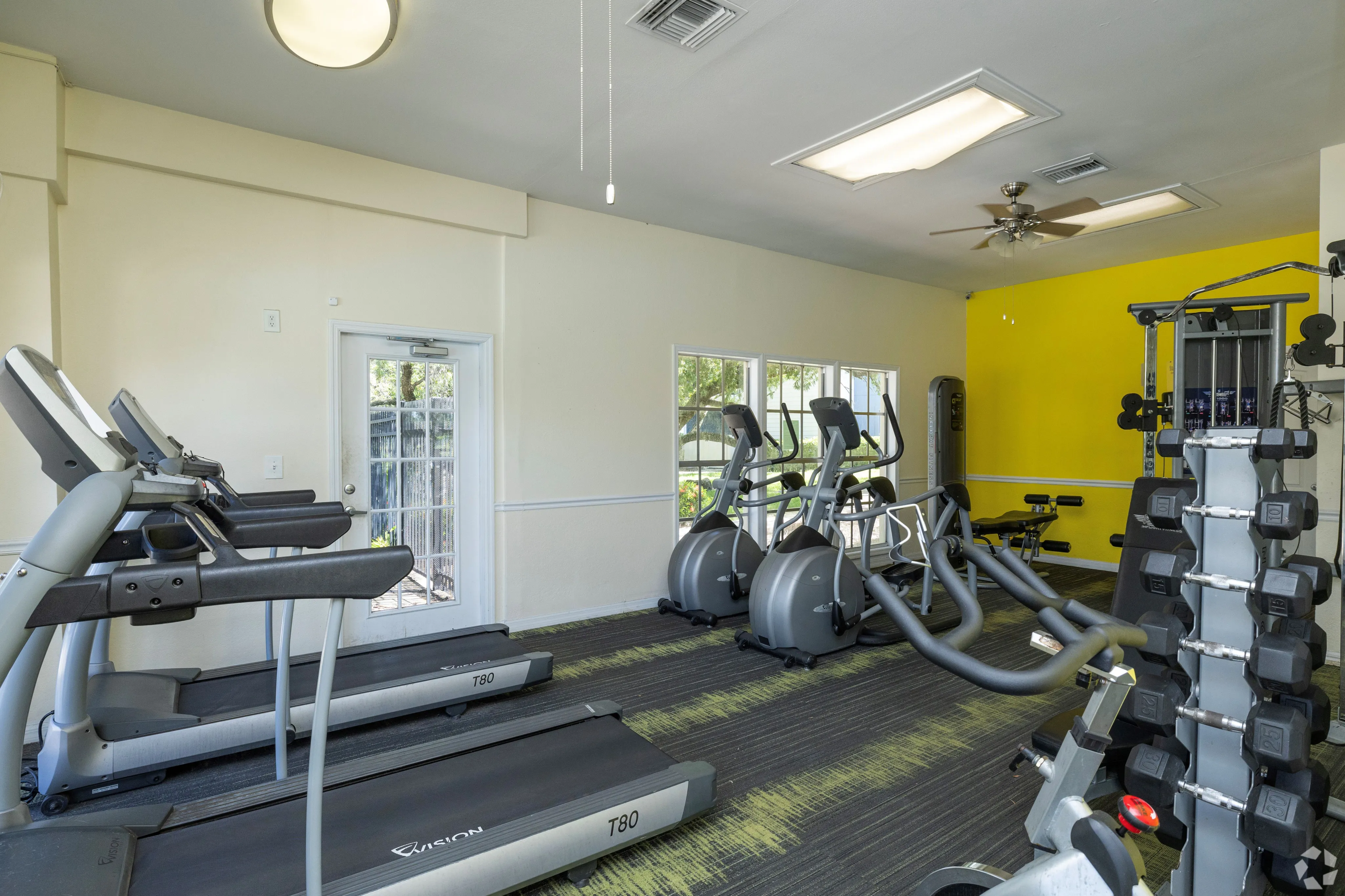 Bright, modern fitness center with state-of-the-art treadmills, elliptical machines, and a variety of free weights.