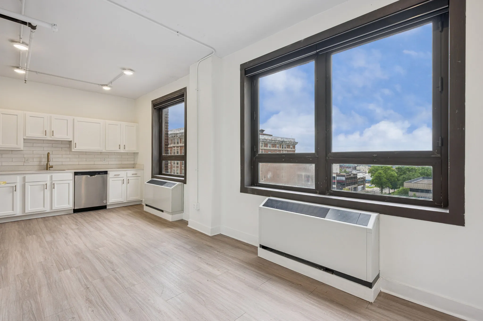 Bright urban kitchen with modern white cabinets, stainless steel appliances, and a picturesque window view.