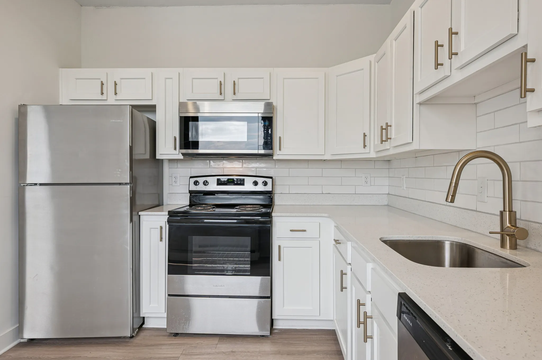 Modern kitchen with sleek stainless steel appliances, elegant white cabinetry, and a spacious quartz countertop.