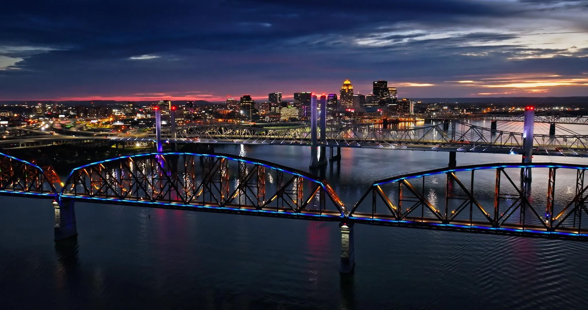 Breathtaking cityscape view with vibrant illuminated bridges over serene water at twilight, creating a captivating urban skyline.