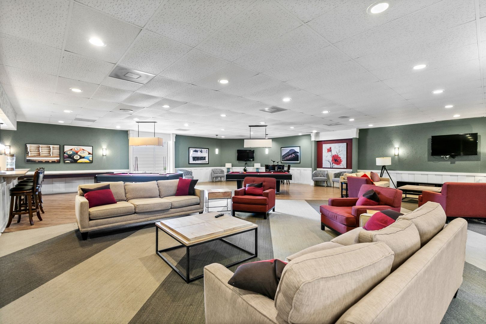 Spacious and inviting community lounge featuring plush seating, modern decor, billiards table, and entertainment area with vibrant wall art.
