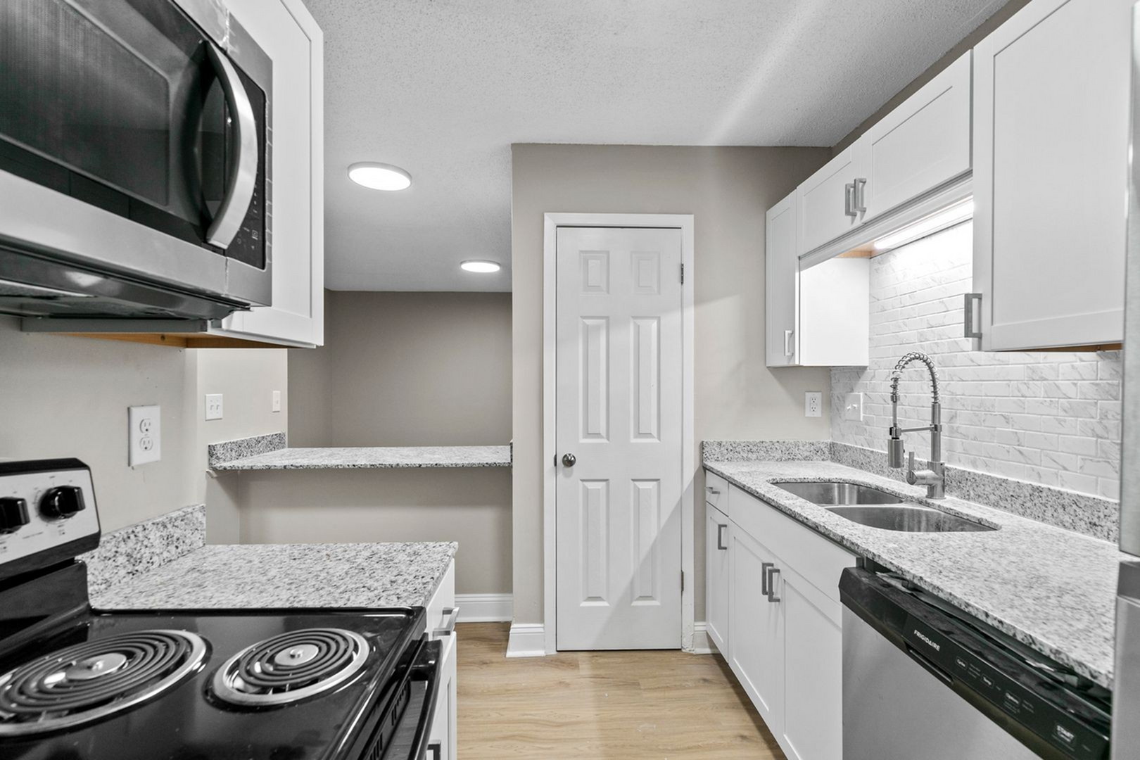 Modern kitchen with sleek granite countertops, stainless steel appliances, and elegant white cabinetry, perfect for gourmet cooking.