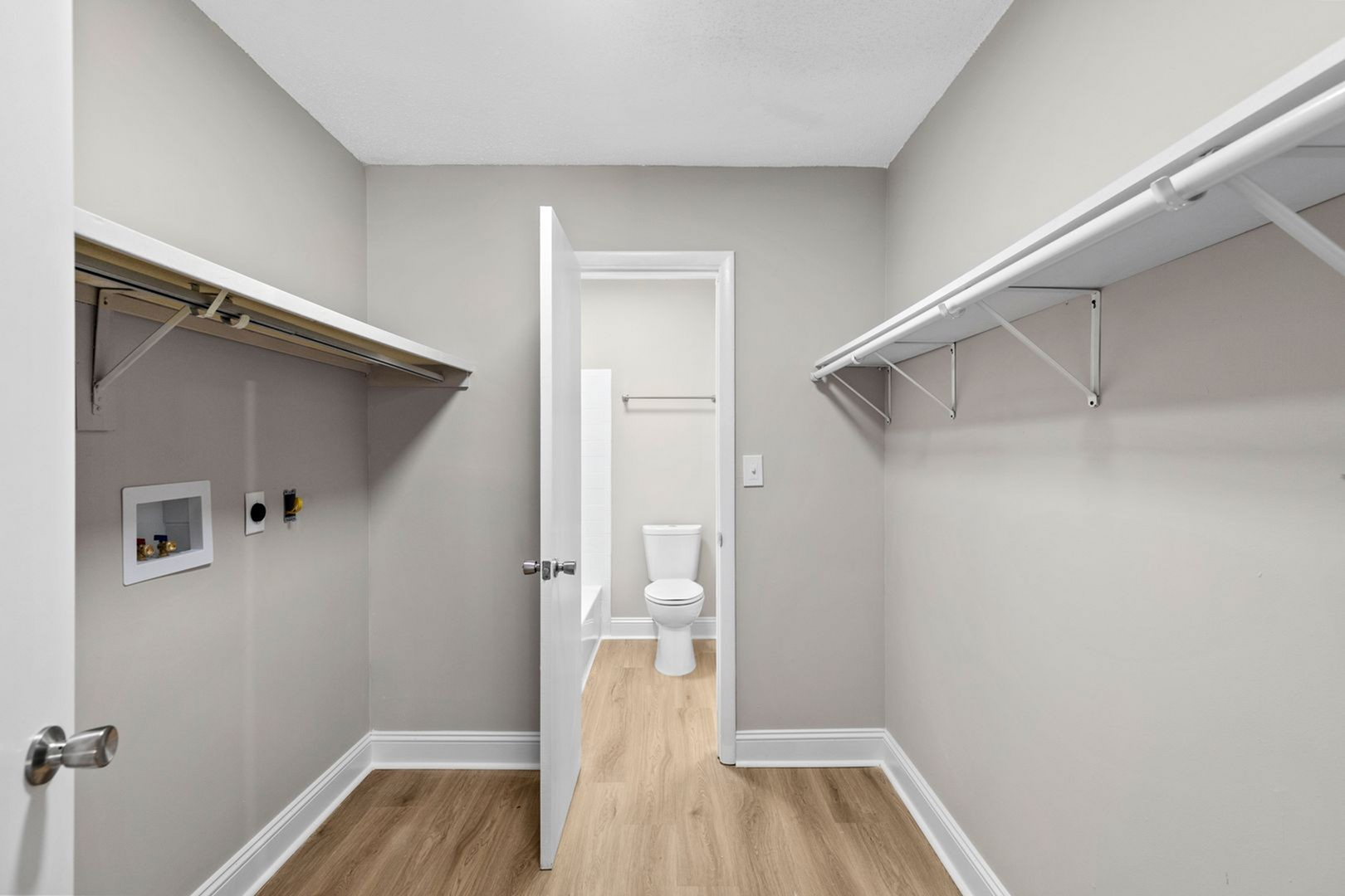 Spacious walk-in closet with ample shelving and sleek design, leading to an elegant en-suite bathroom.