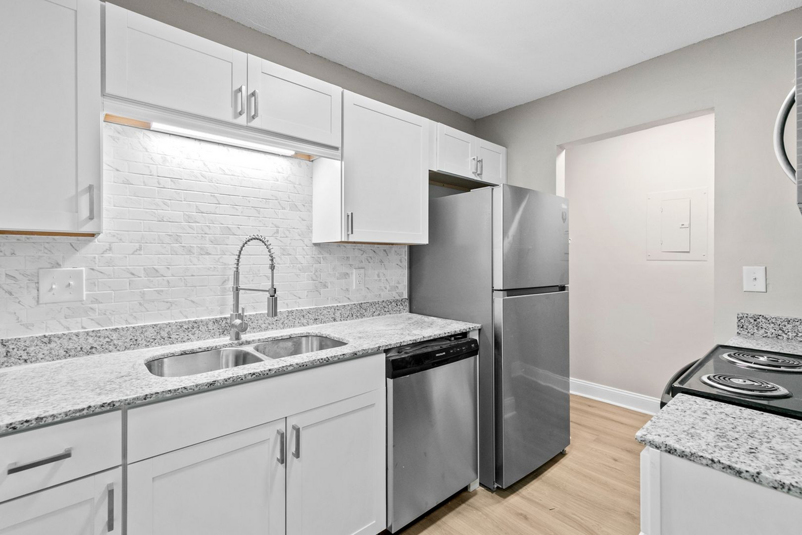 Modern kitchen with sleek stainless steel appliances, elegant granite countertops, and stylish white cabinetry, perfect for contemporary living.