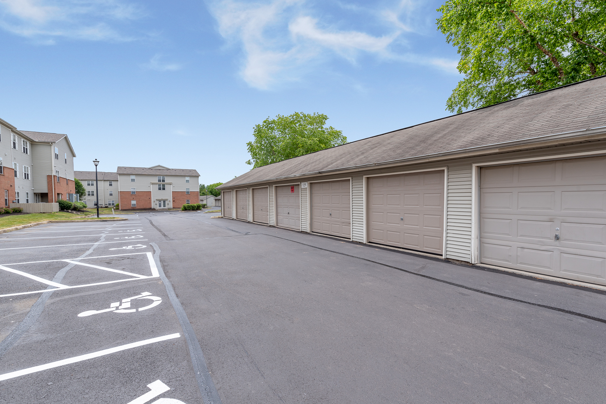 Inviting apartment complex with convenient parking and private garages, set under a clear, blue sky.