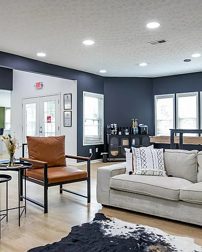 Stylish living area with modern furnishings including a beige sofa, leather chairs, and an accent wall.