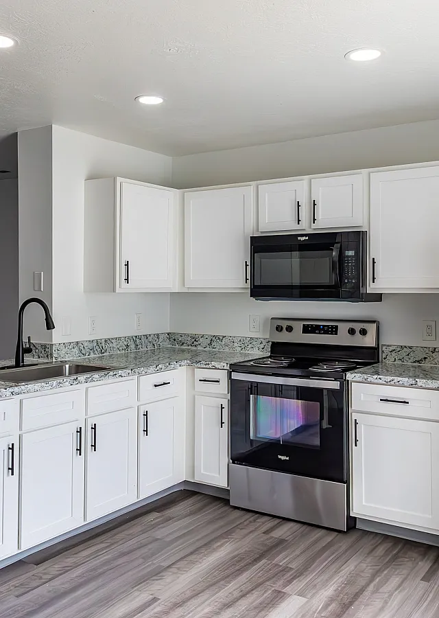 Contemporary kitchen with white cabinetry, stainless steel appliances, and granite countertops.