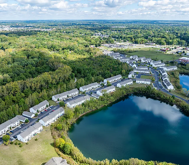 Aerial view of a picturesque residential community surrounded by lush greenery and serene water bodies.